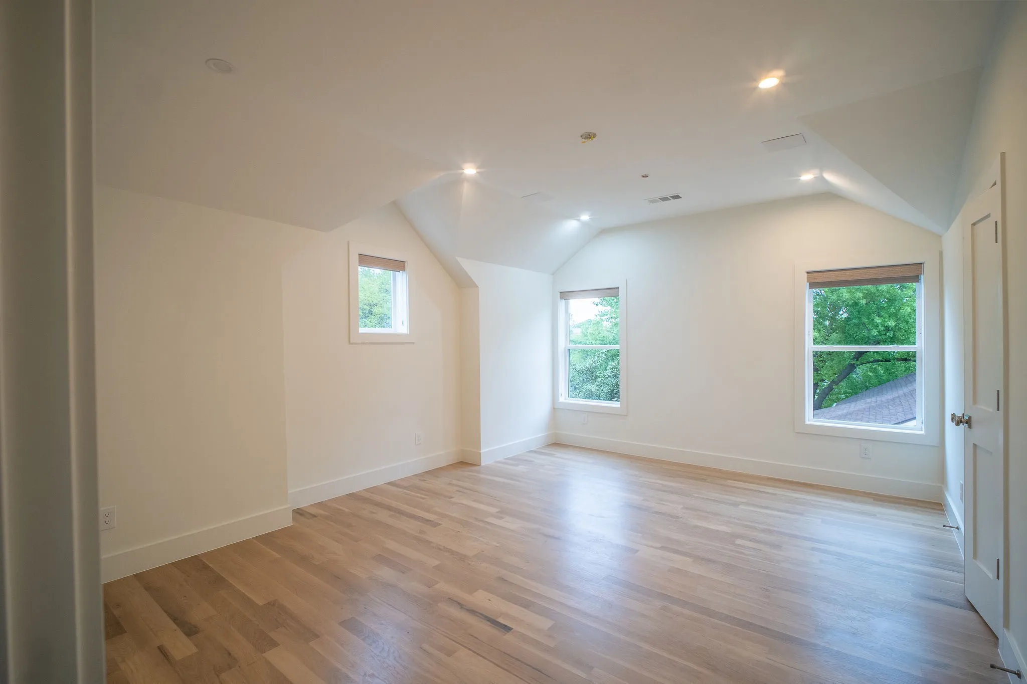 This room features light hardwood flooring, white walls, and recessed lighting