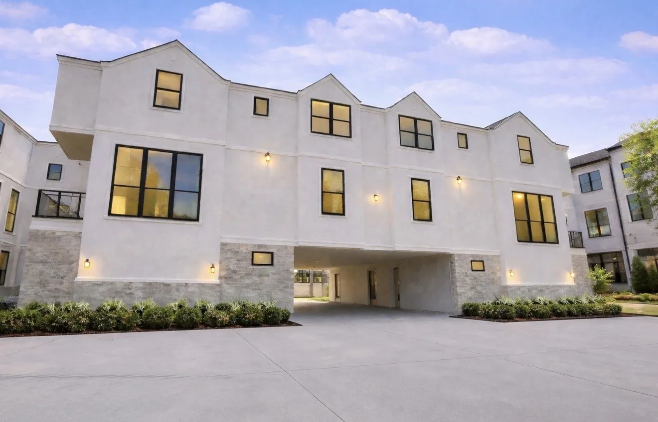 The property features a white exterior with stone accents, black-framed windows, and exterior lighting fixtures