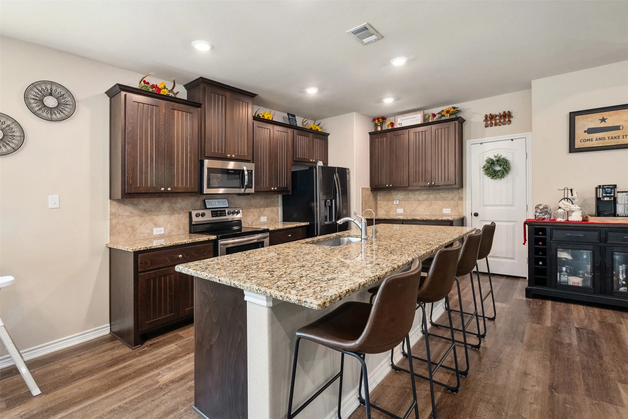 Kitchen featuring dark wood cabinetry, stainless steel appliances, a tile backsplash, and granite countertops