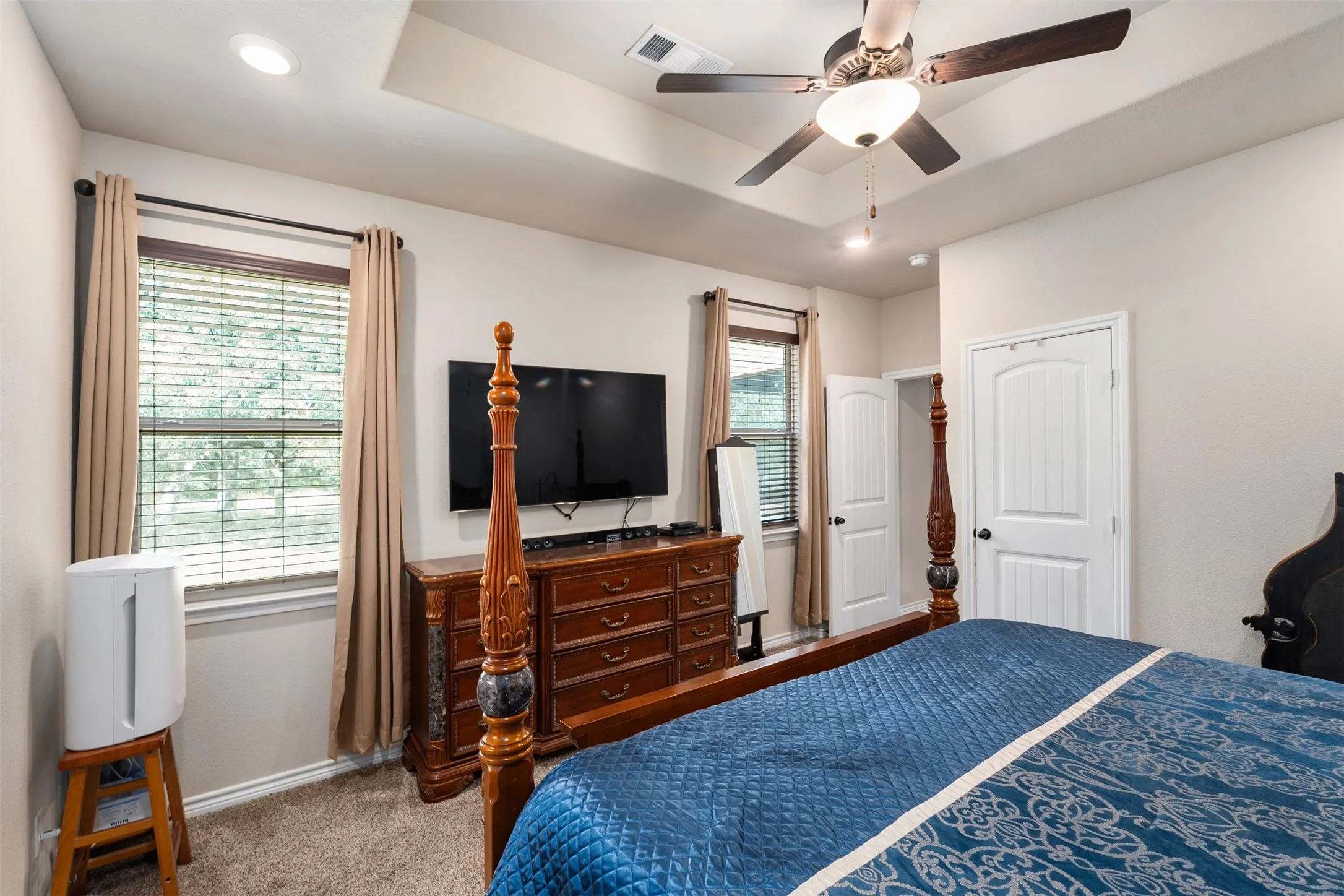 Carpeted interior space featuring a tray ceiling, recessed lighting, and a ceiling fan