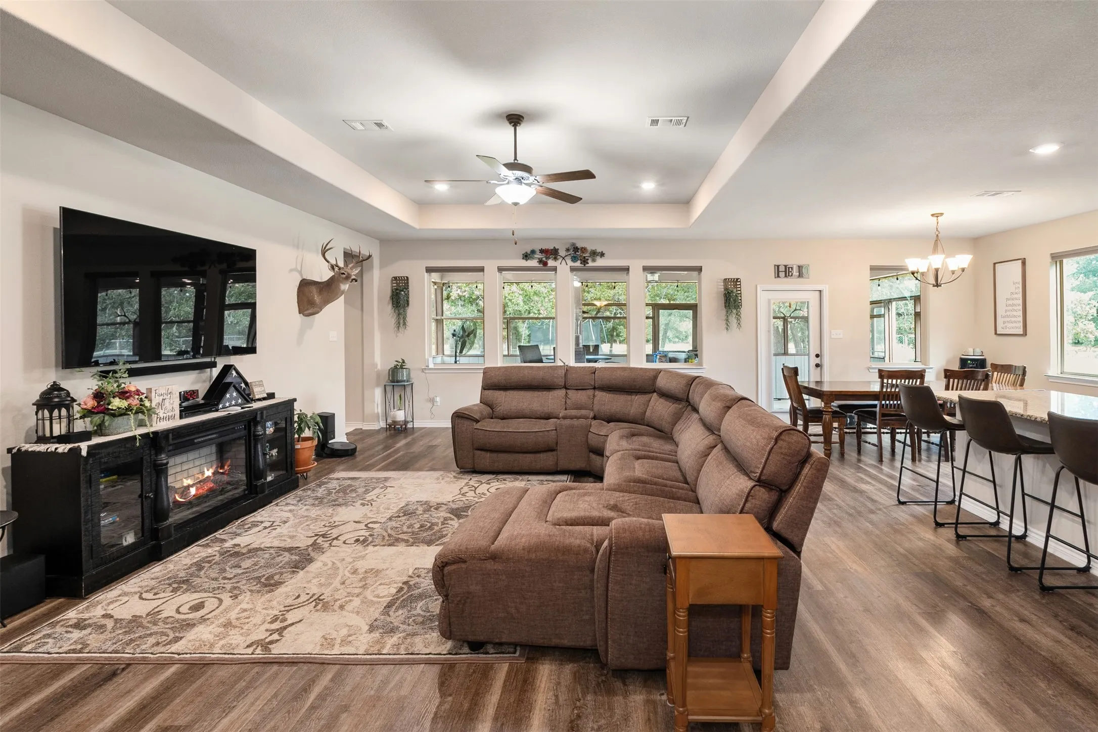 Open-concept living space featuring wood-finish flooring, recessed lighting, a tray ceiling, and a dining area with pendant lighting