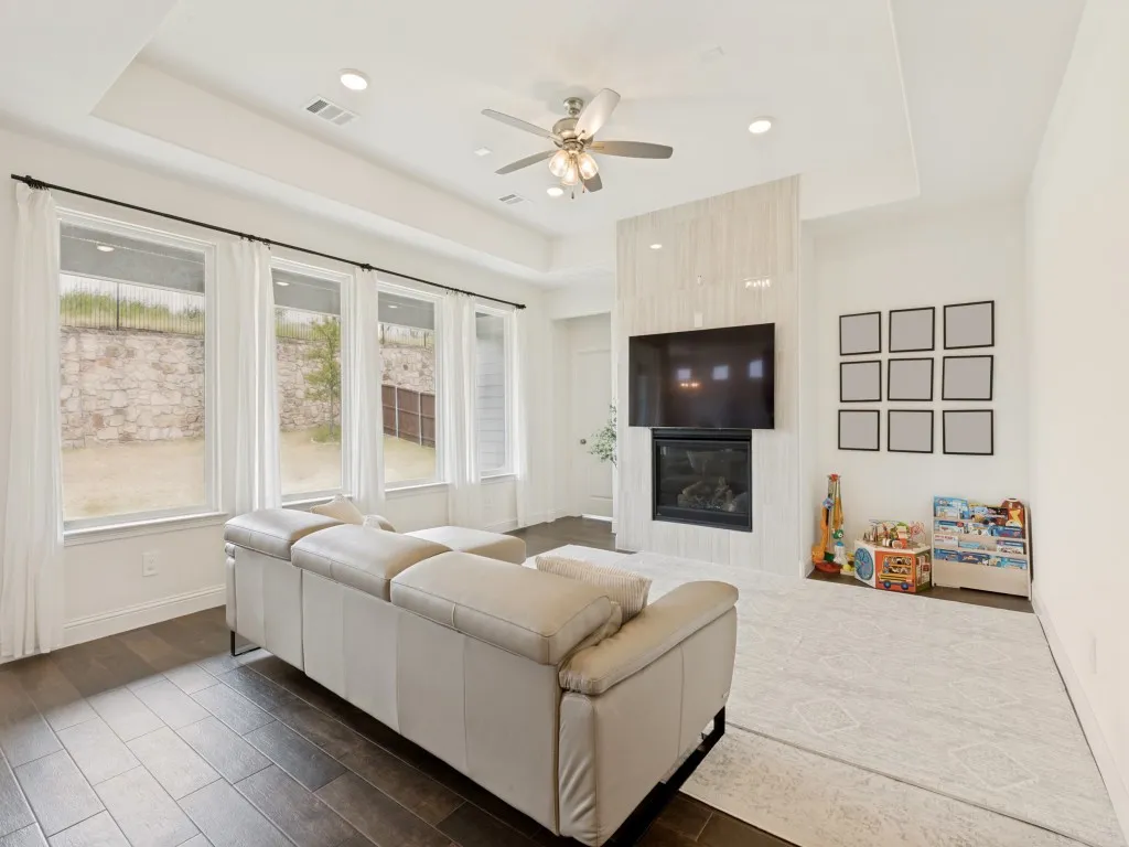 Living area featuring dark wood-finish tile flooring and a tray ceiling with recessed lighting