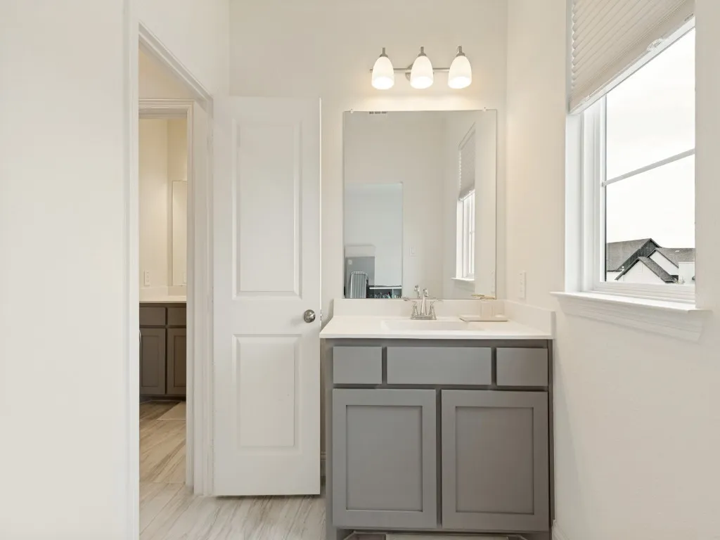Bathroom featuring a gray vanity with a white countertop, chrome faucet, and rectangular mirror