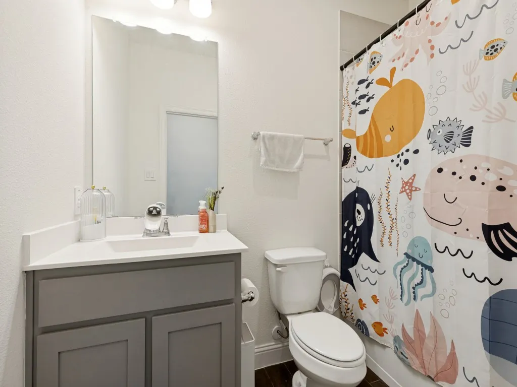 Bathroom featuring a light gray vanity with a white countertop and integrated sink, a wall-mounted mirror, and overhead lighting