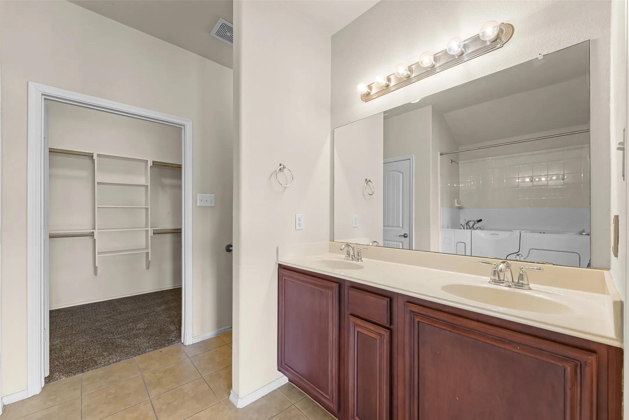 Bathroom featuring a dual vanity with a light-toned countertop and wood-finish cabinetry