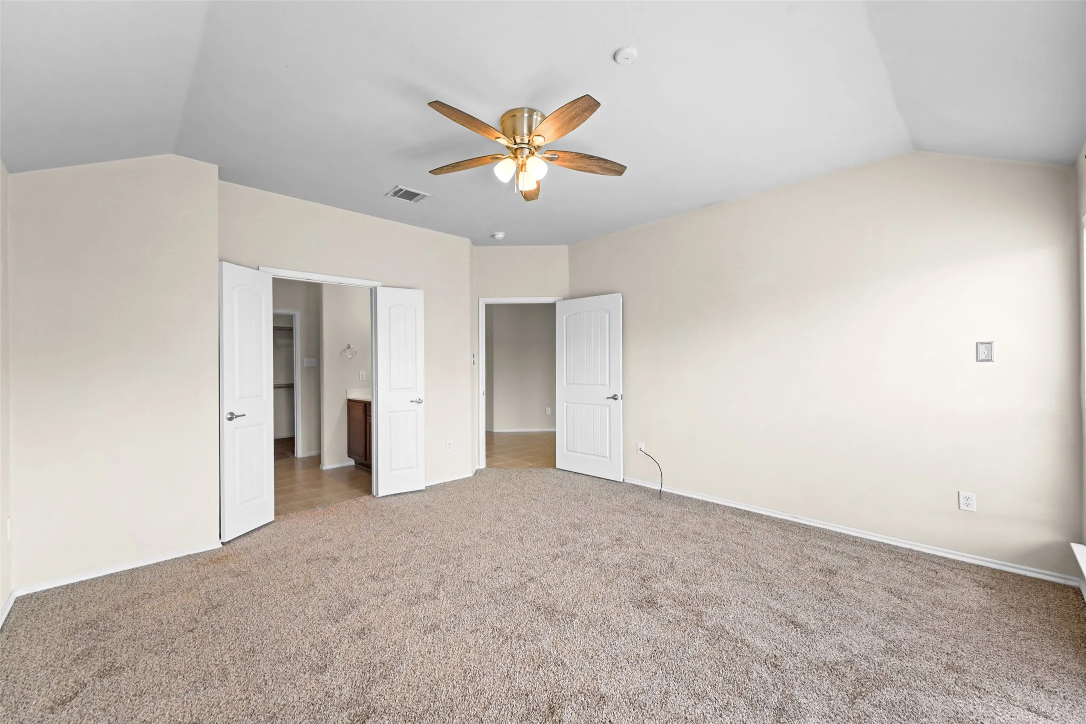Carpeted interior room featuring a vaulted ceiling and a ceiling fan with light fixture