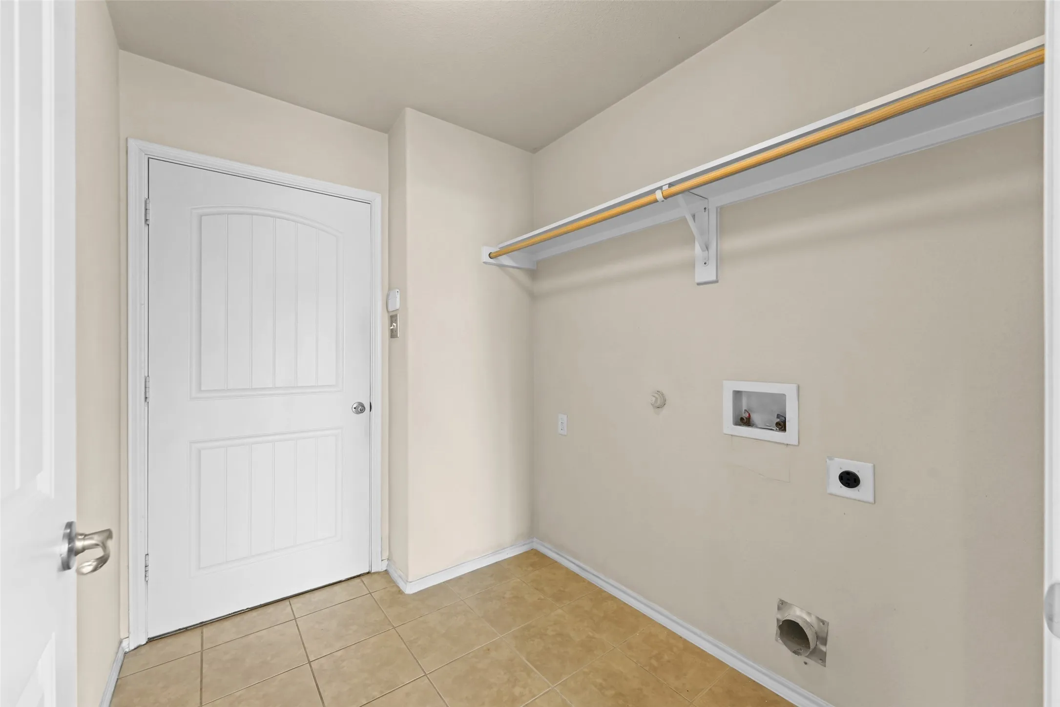 Laundry area featuring tile flooring, neutral wall paint, and a white paneled door