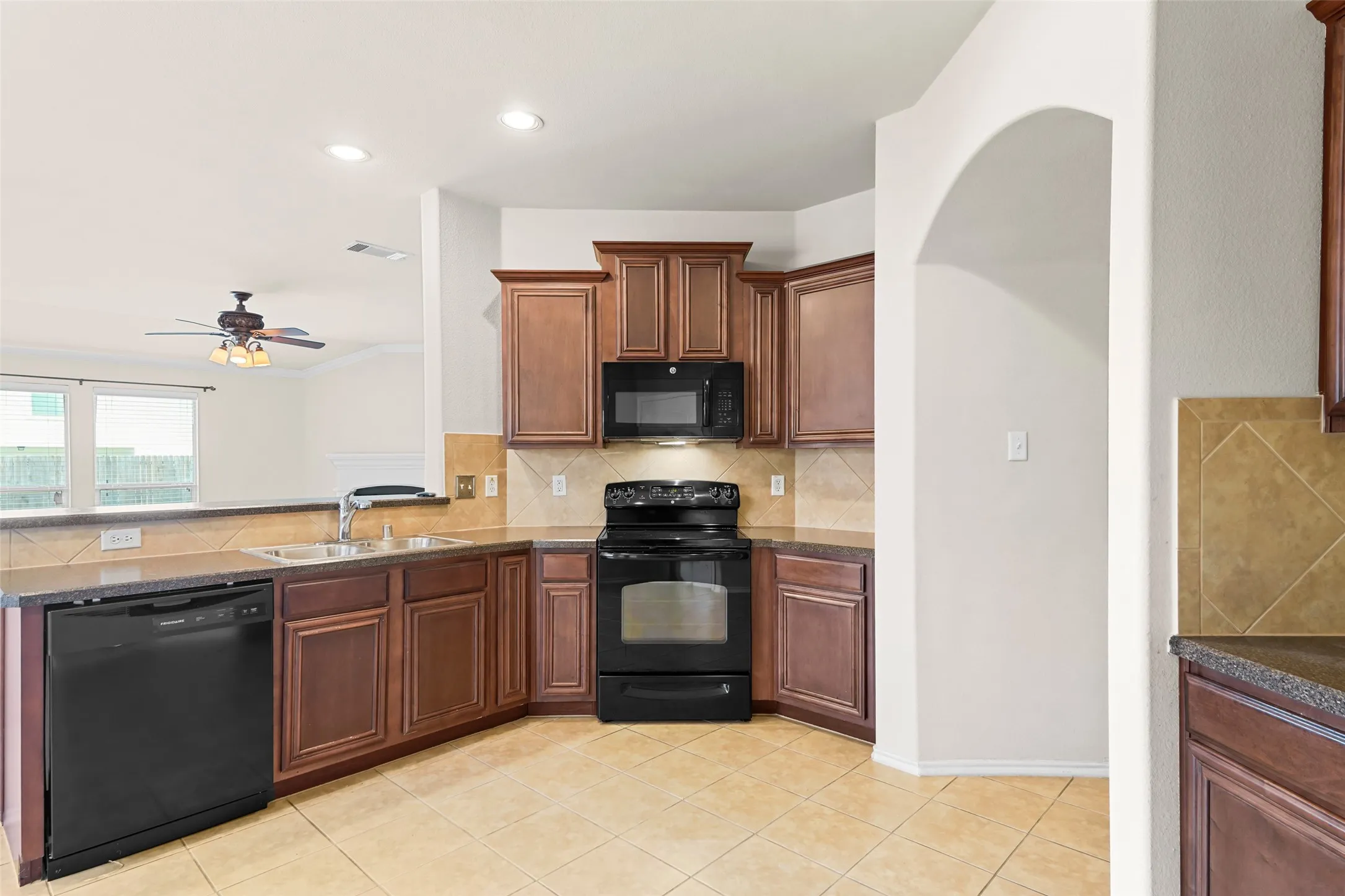 Kitchen featuring black appliances, wood-finish cabinetry, and tile flooring
