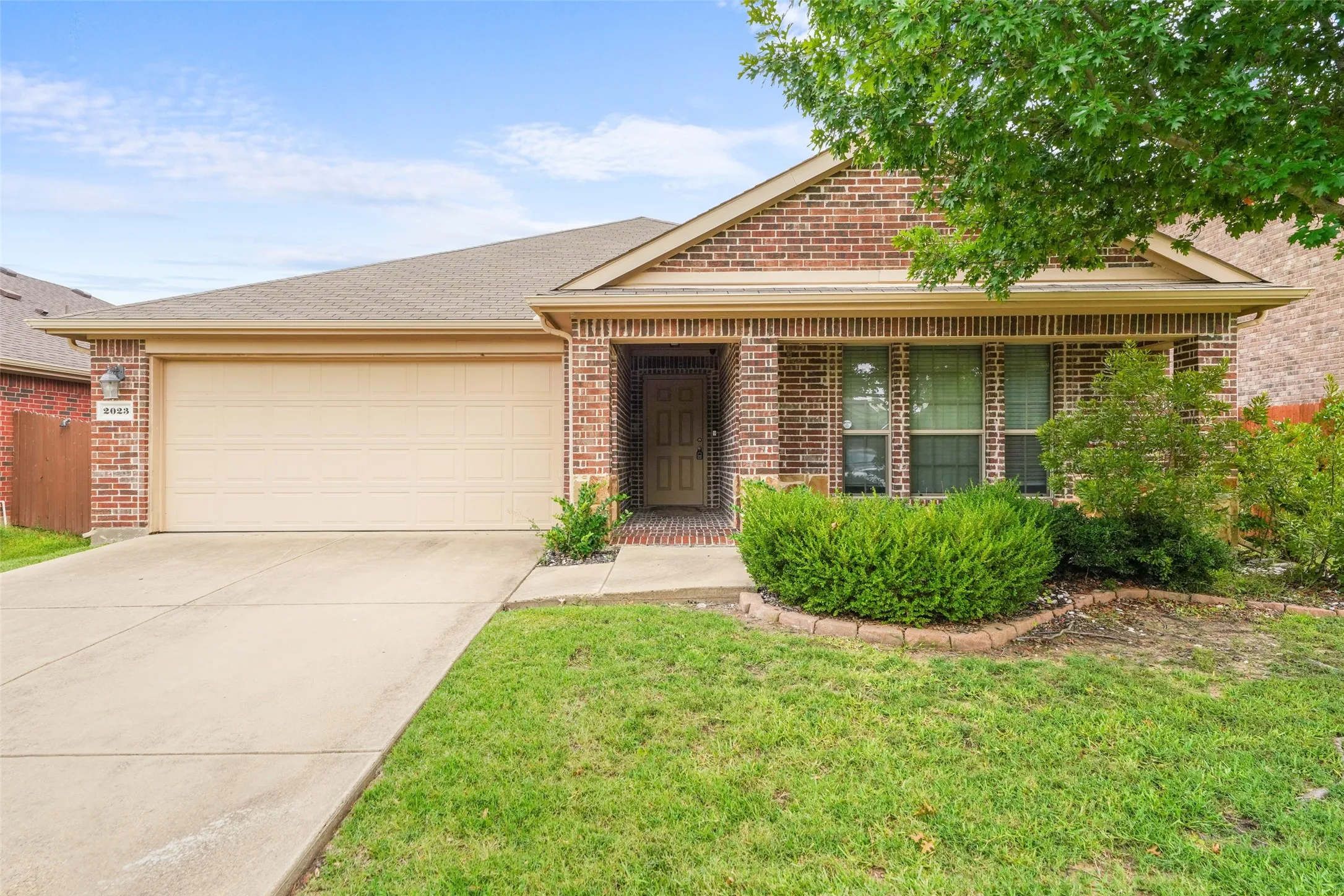 Brick facade home featuring a two-car garage, concrete driveway, and covered entry
