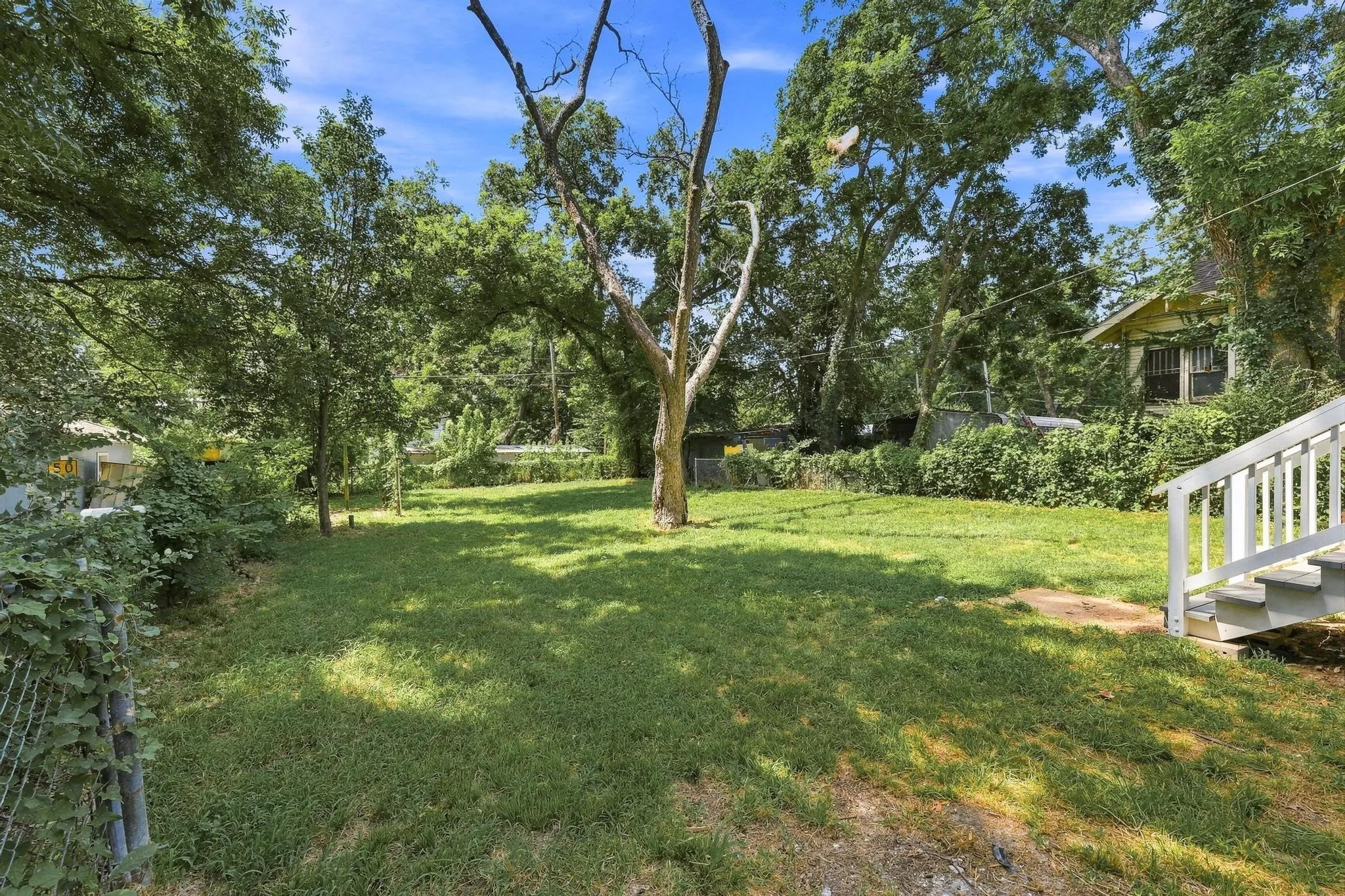 Expansive green lawn with mature trees and perimeter fencing