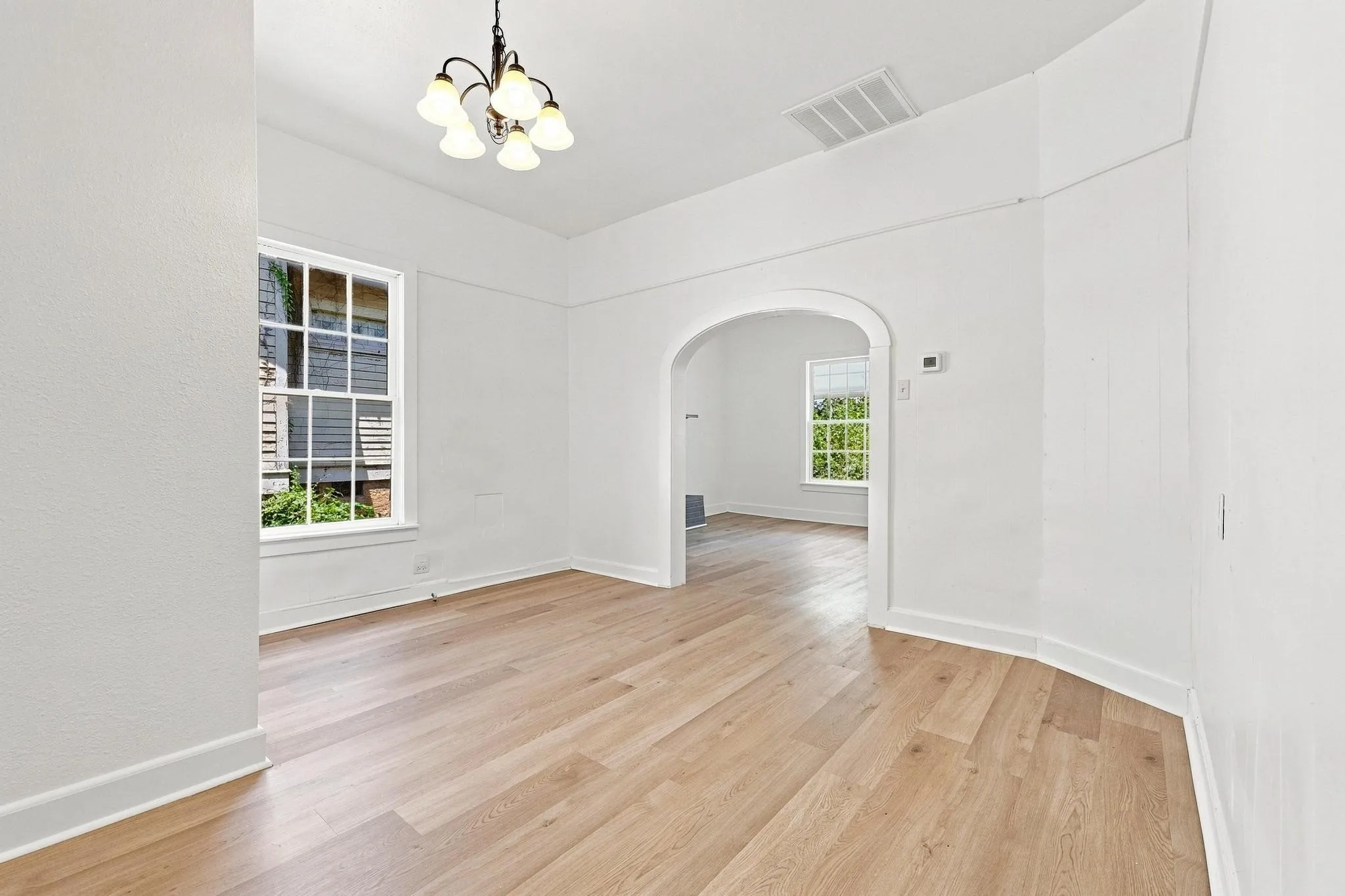 Dining room featuring light wood-finish flooring, crisp white walls, and a five-light chandelier