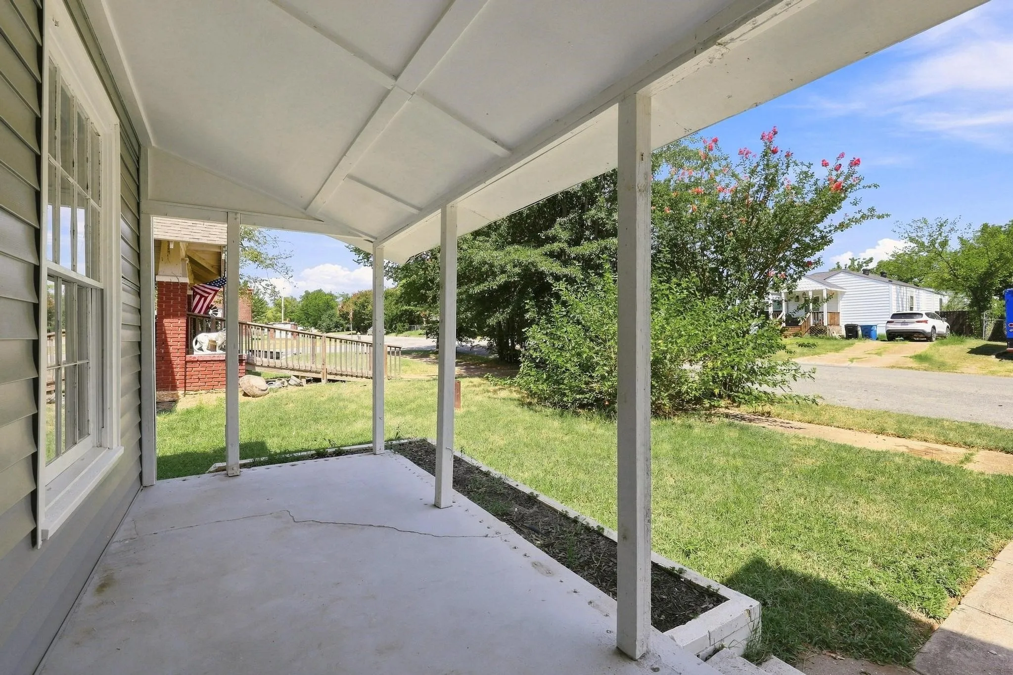 Covered concrete porch with white support posts