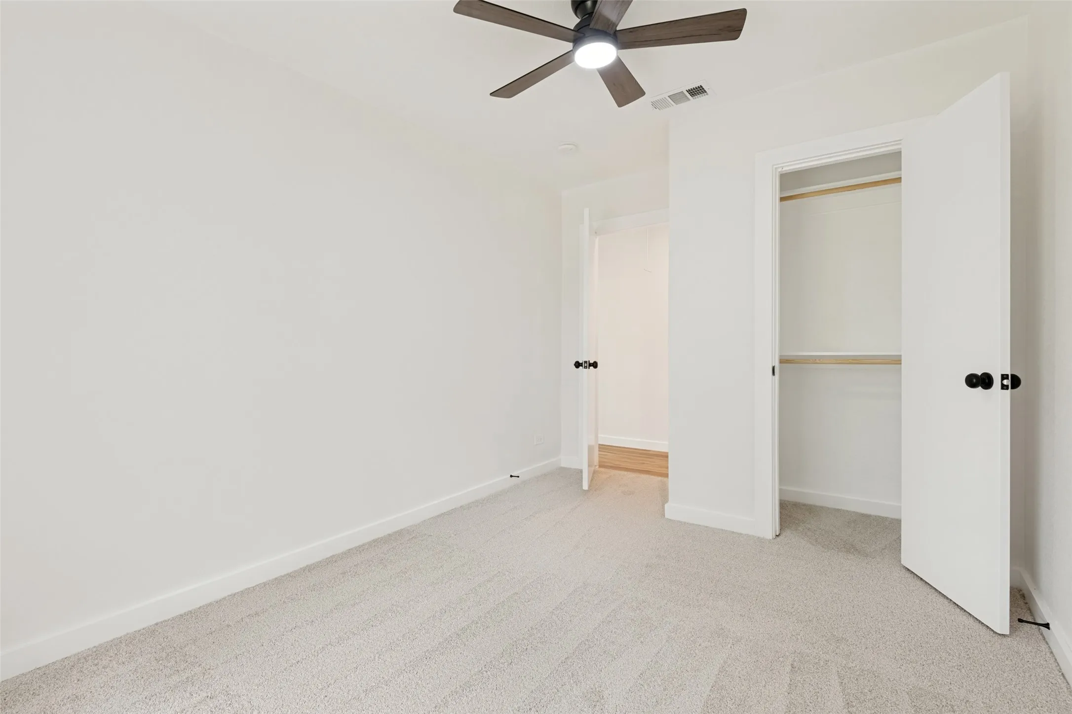 Carpeted room featuring a ceiling fan with integrated lighting, white walls, and a closet with bi-fold doors