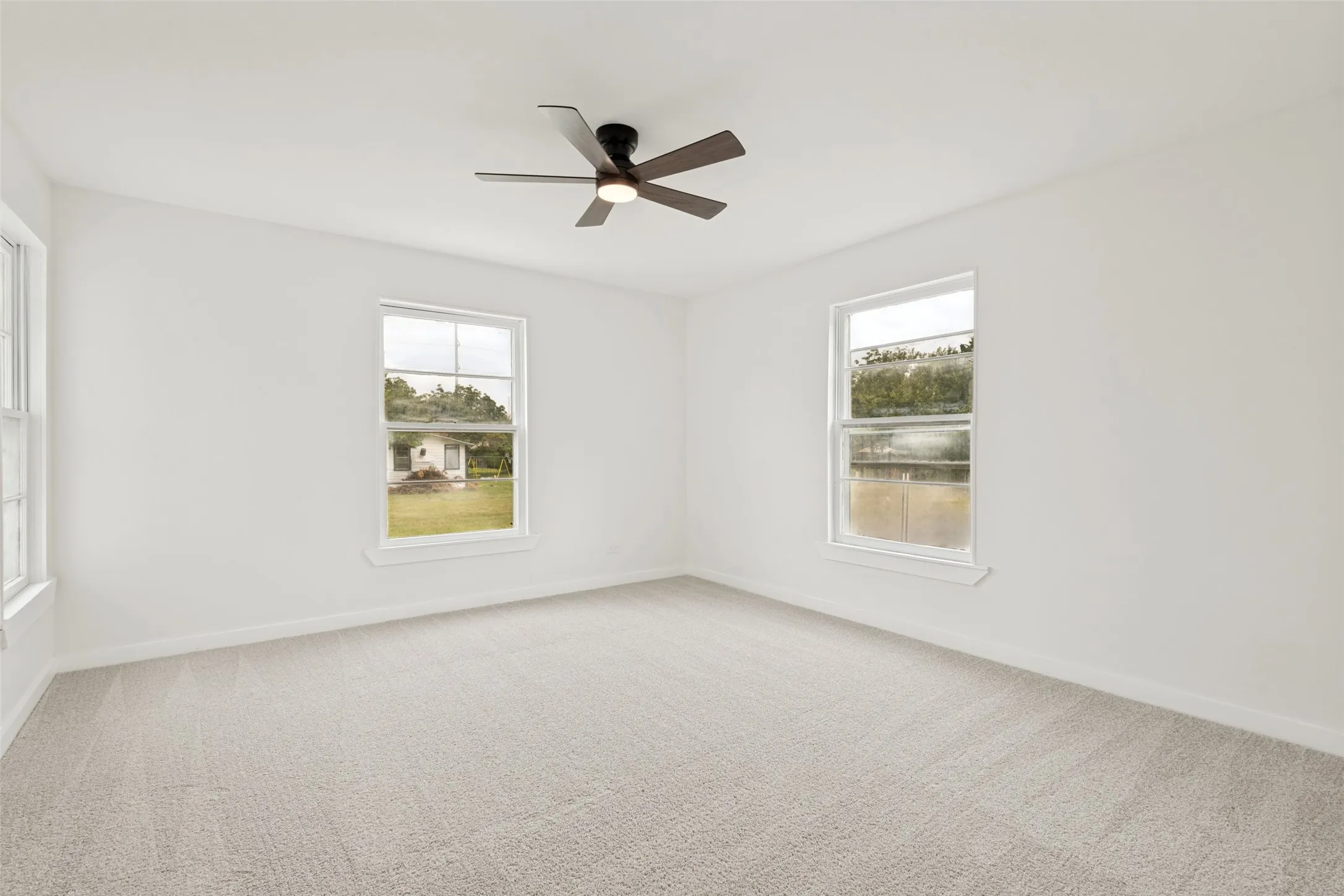 Spacious room featuring light-toned carpet flooring and white painted walls