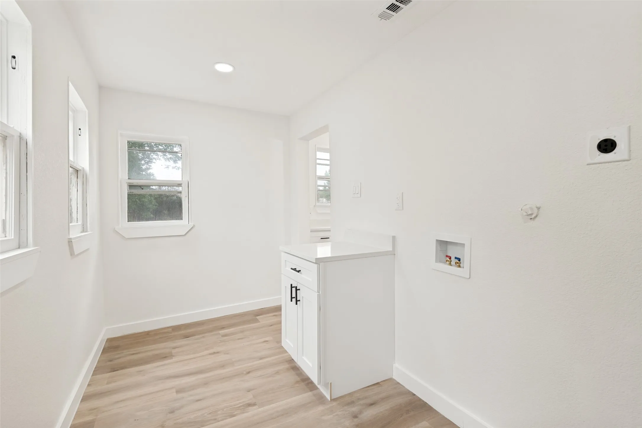 Utility space featuring light wood-finish flooring, white walls, and recessed lighting