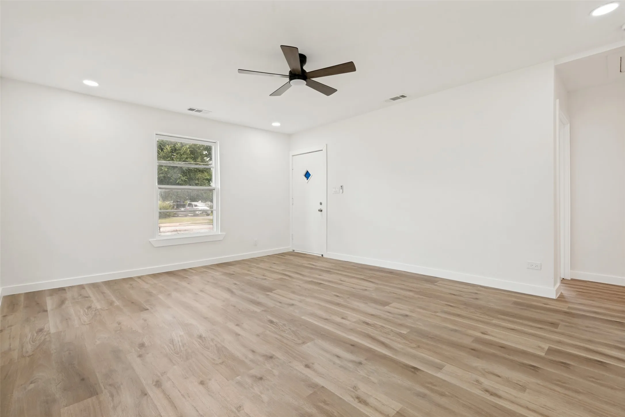 Spacious room featuring wood-finish flooring, recessed lighting, and a contemporary ceiling fan