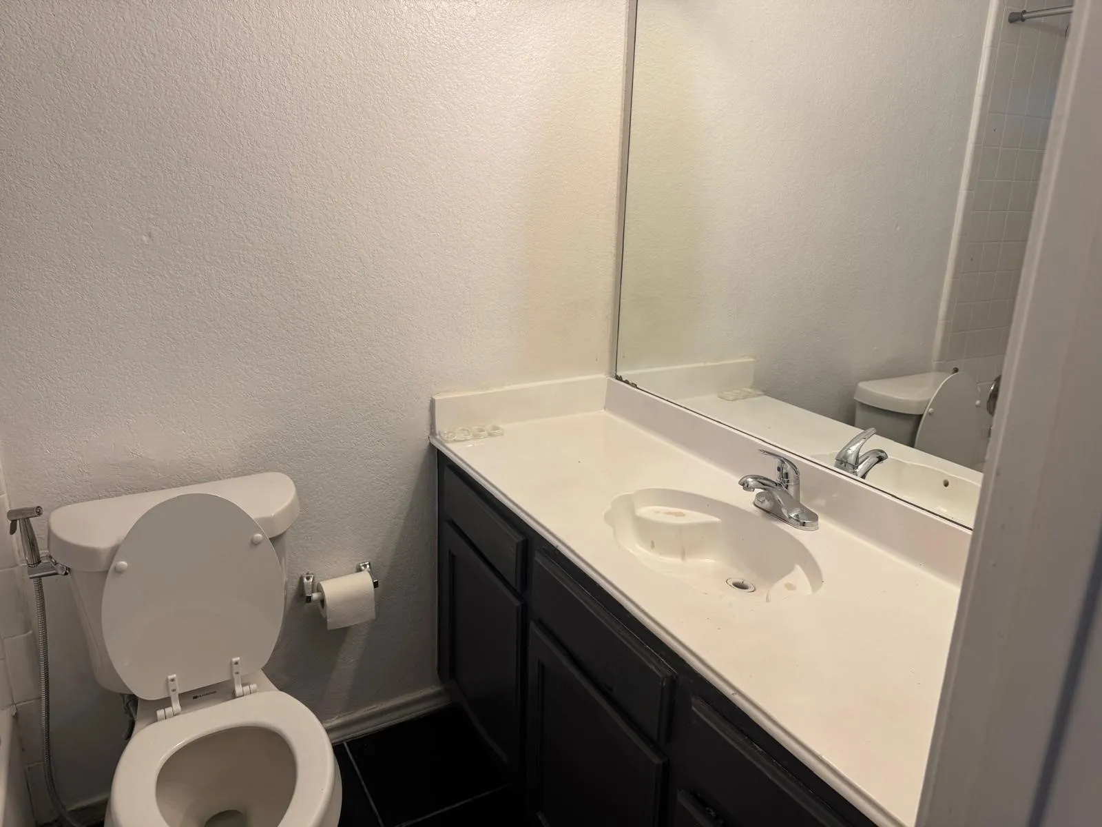 Bathroom featuring a dark wood-finish vanity with a white countertop and integrated sink, a chrome faucet, and a large wall-mounted mirror