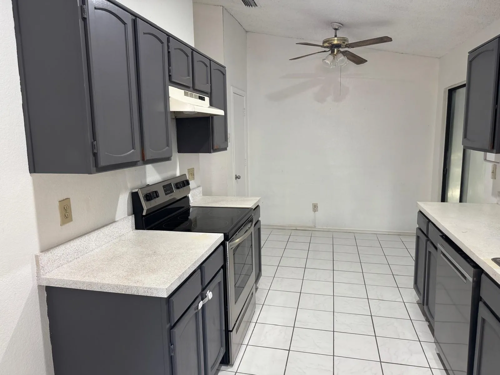 Kitchen featuring dark gray cabinetry, light speckled countertops, and white tile flooring
