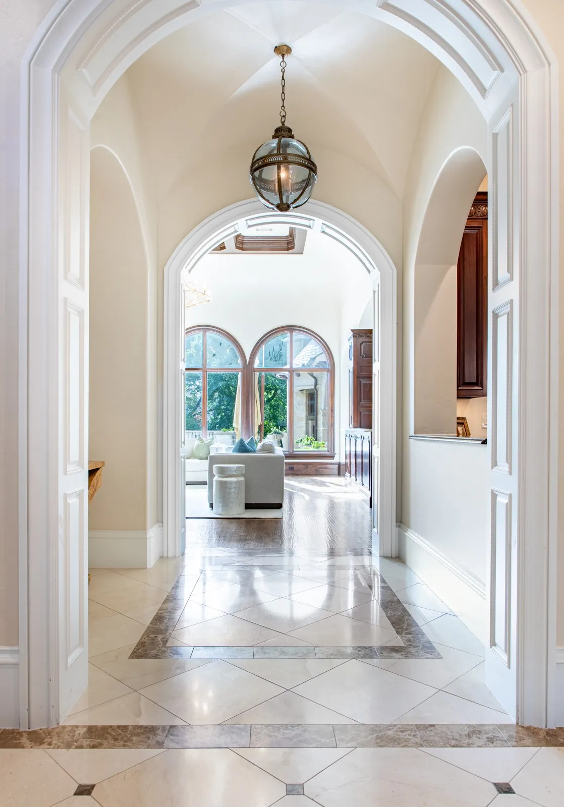Hallway featuring a charming barreled ceiling, decorative wood archways, and a globe pendant light fixture