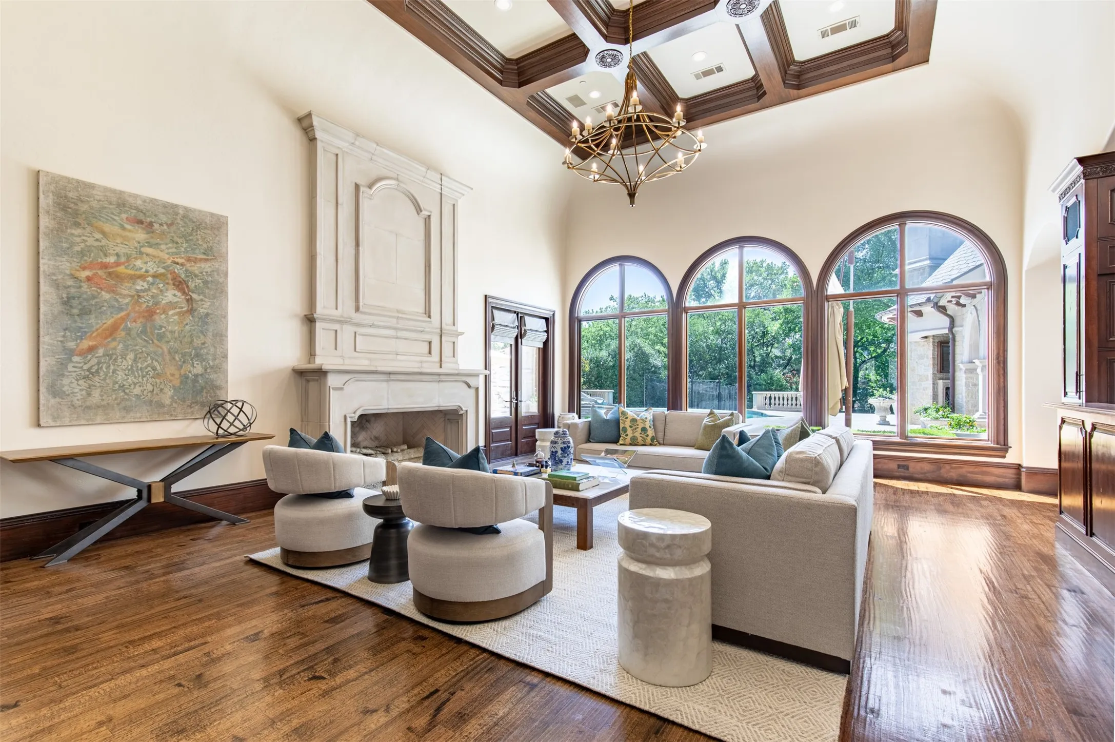 Soaring two-story curved ceiling with integrate coffered wood-finish ceiling, statement piece cast concrete fireplace, new designer brass chandelier, and arched wood glad windows and doors
