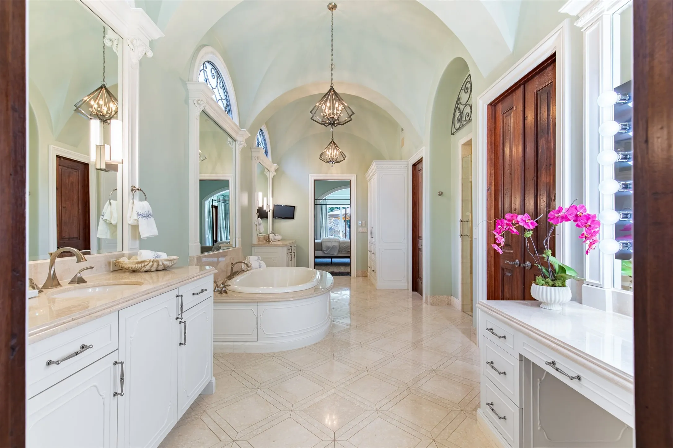 Vaulted ceilings highlight this bathroom featuring a built-in jetted tub, dual vanity, separate make-up vanity, and dual closets