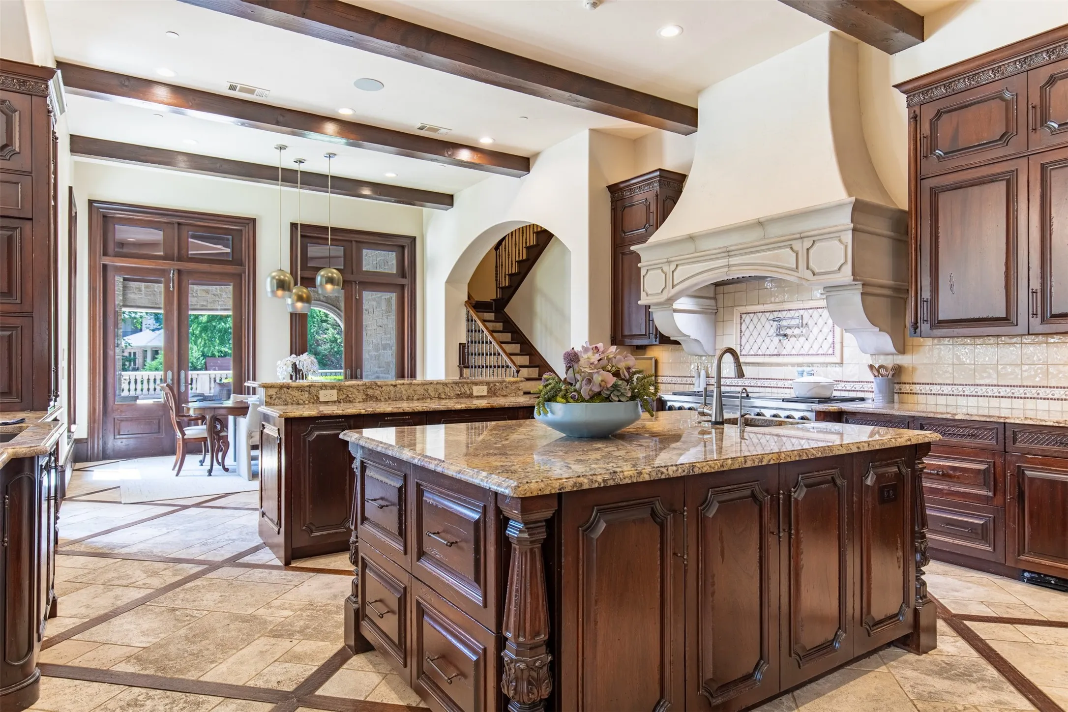 Sophistcated gourmet kitchen featuring custom luxury wood cabinetry, granite countertops, a large center island, and a decorative cast concrete range hood. Sub-Zero column glass refrigerator, dual dishwashers, 2 fridge drawers, 48 gas Commerical grade gas range, built-in Wolf oven, vegetable sink with filtered and pot filler