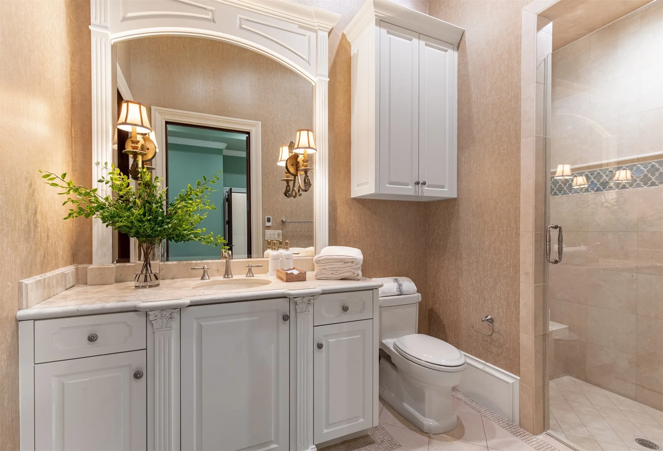 Downstairs guest bathroom with light-toned countertop, dual sinks, and white cabinetry featuring decorative pilasters