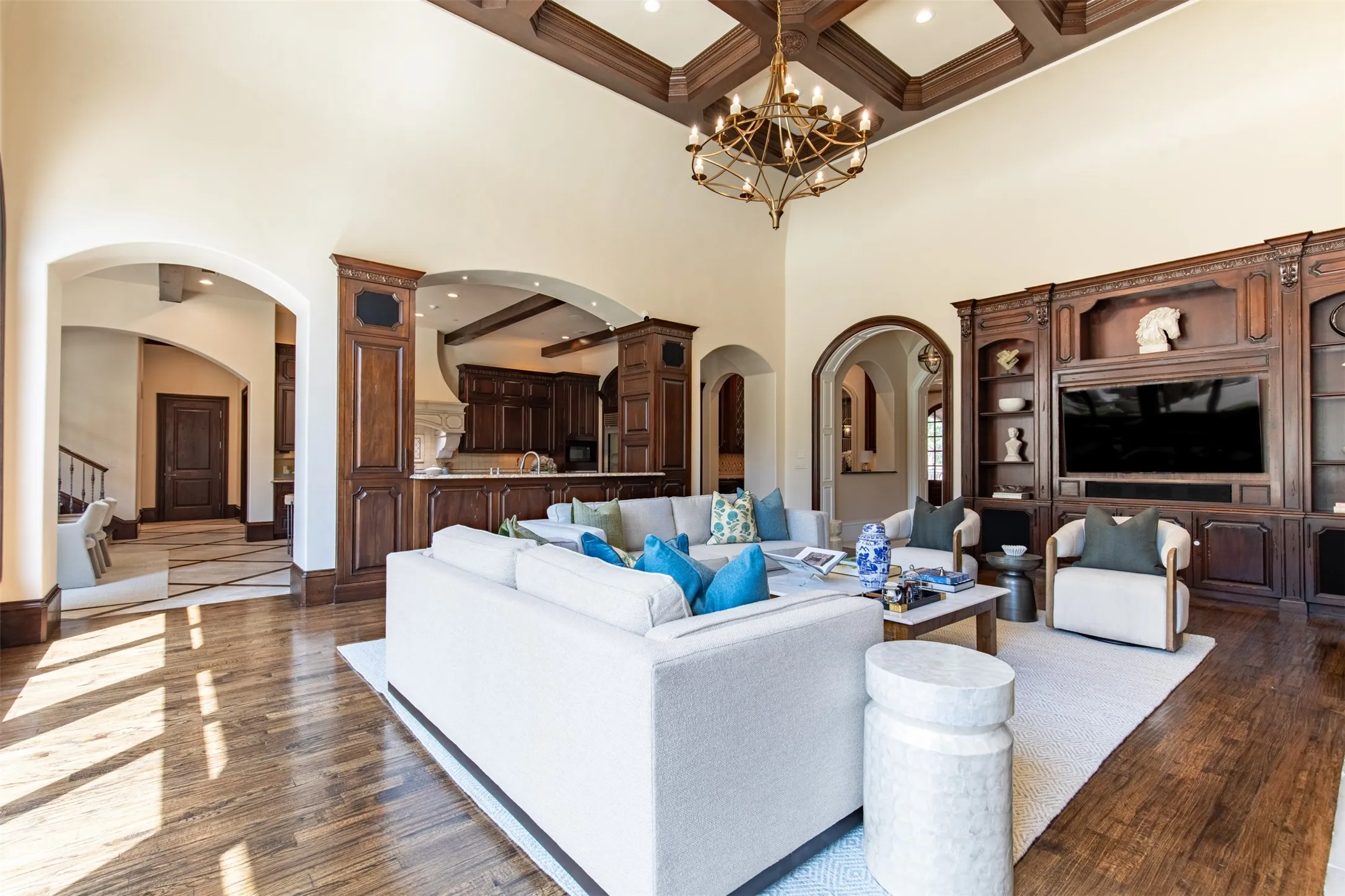 Grand living area featuring soaring ceilings, nail down hardwoods, ornate wood trim details and new designer brass chandlier