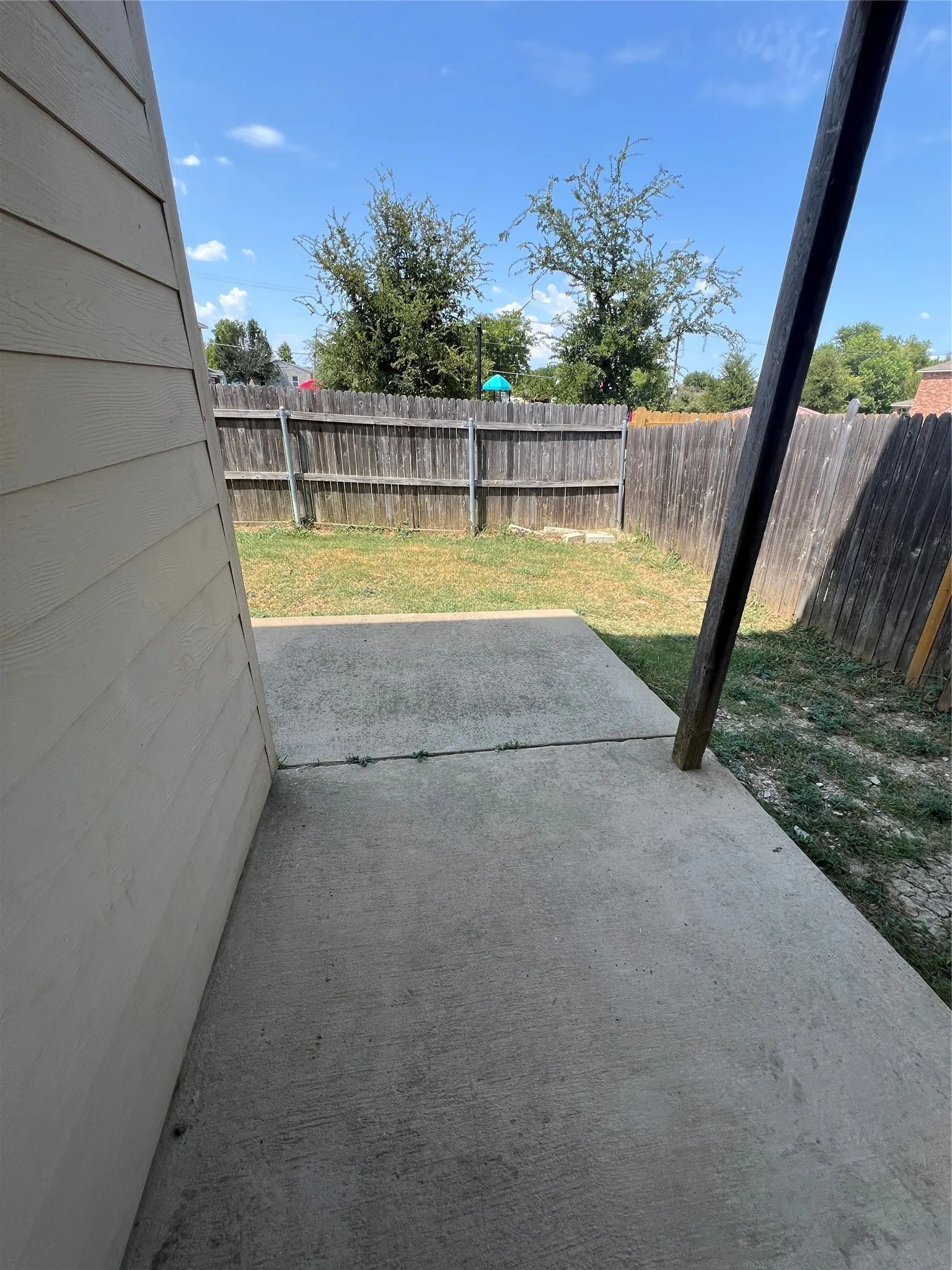 Concrete patio with a wood privacy fence and a grassy area