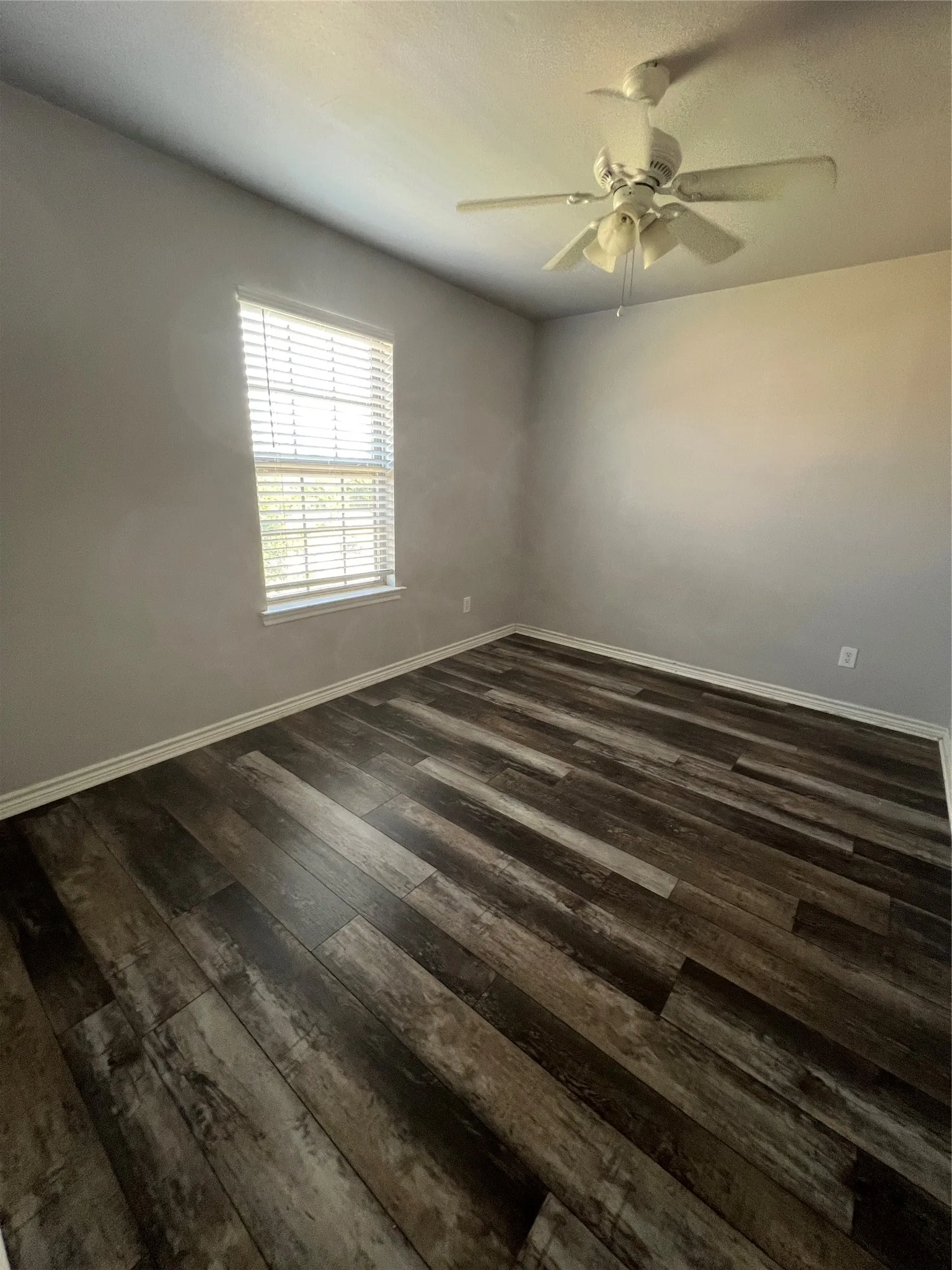 Wood-finish flooring, neutral wall tones, ceiling fan, window with blinds