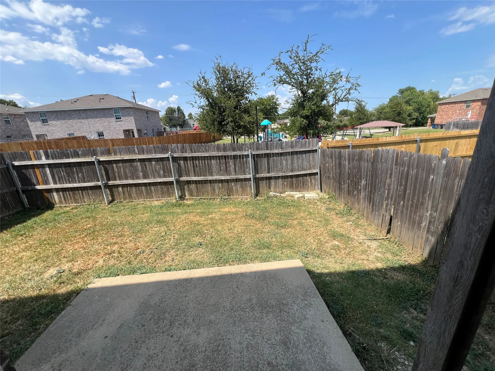 Private fenced backyard with a concrete patio