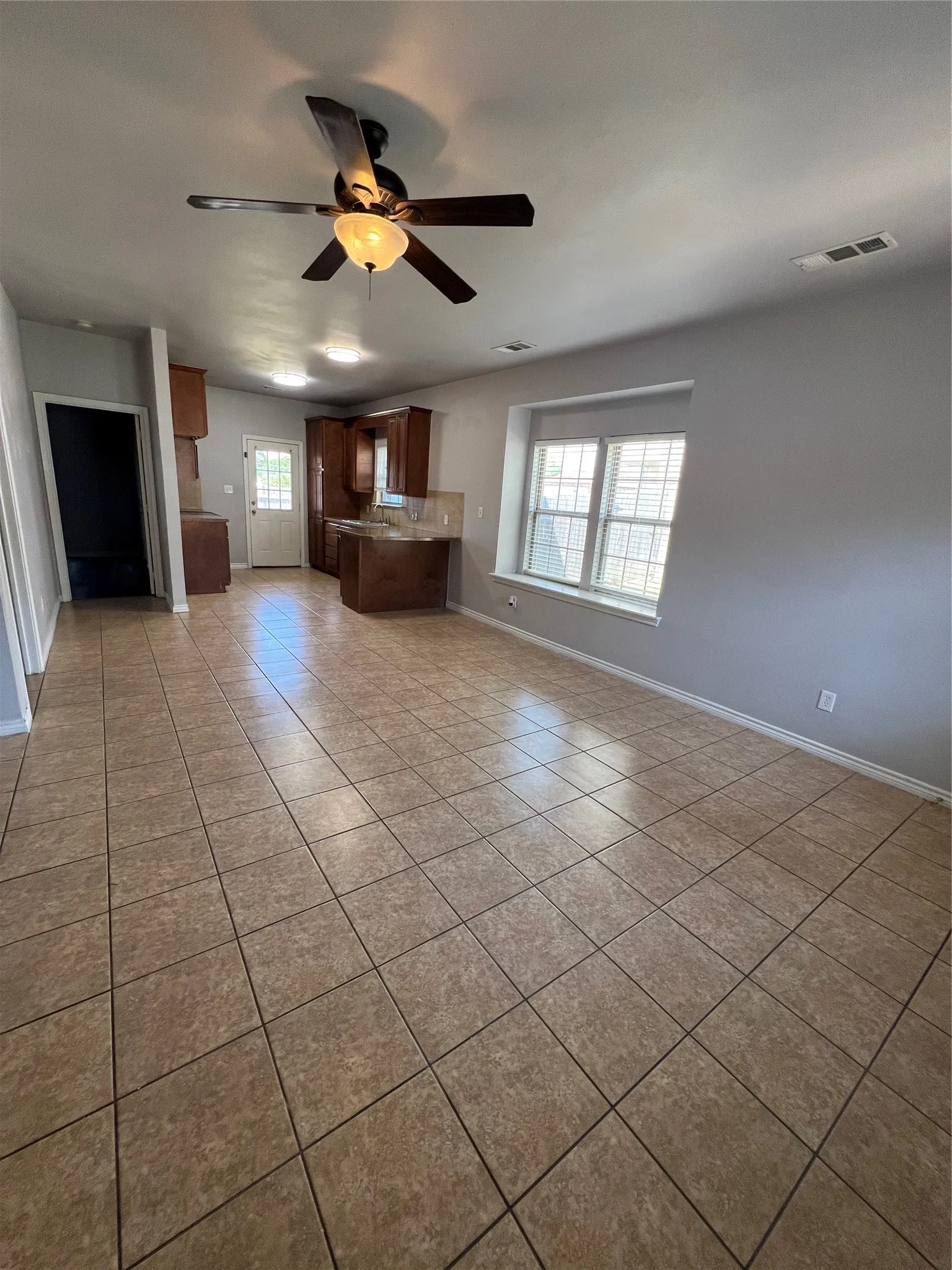 Spacious room featuring tile flooring, a ceiling fan with integrated lighting, recessed lighting, and a large window