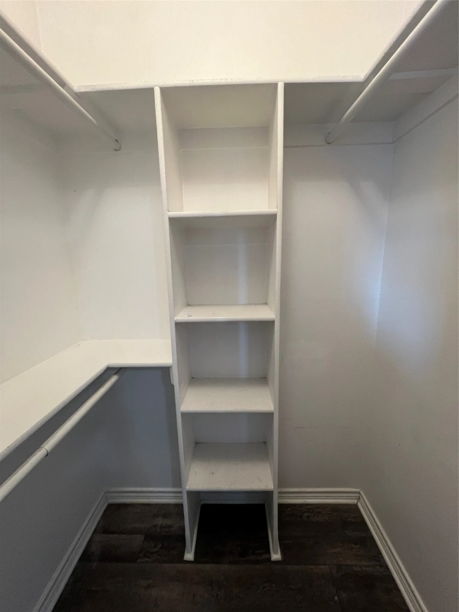 Built-in shelving unit with multiple shelves, white walls, and wood-finish flooring