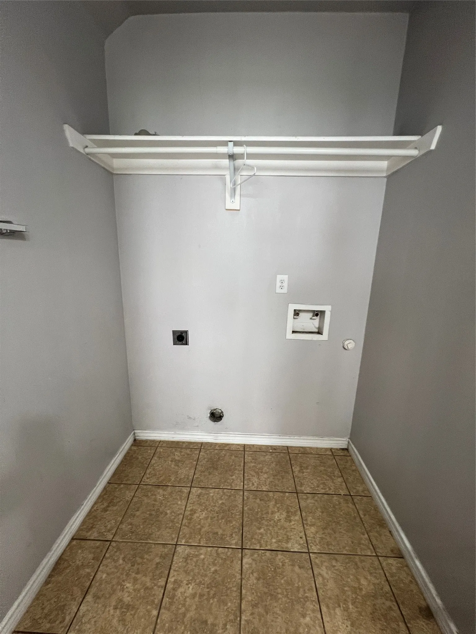 Utility area with tiled flooring, a built-in white shelf, and appliance hookups