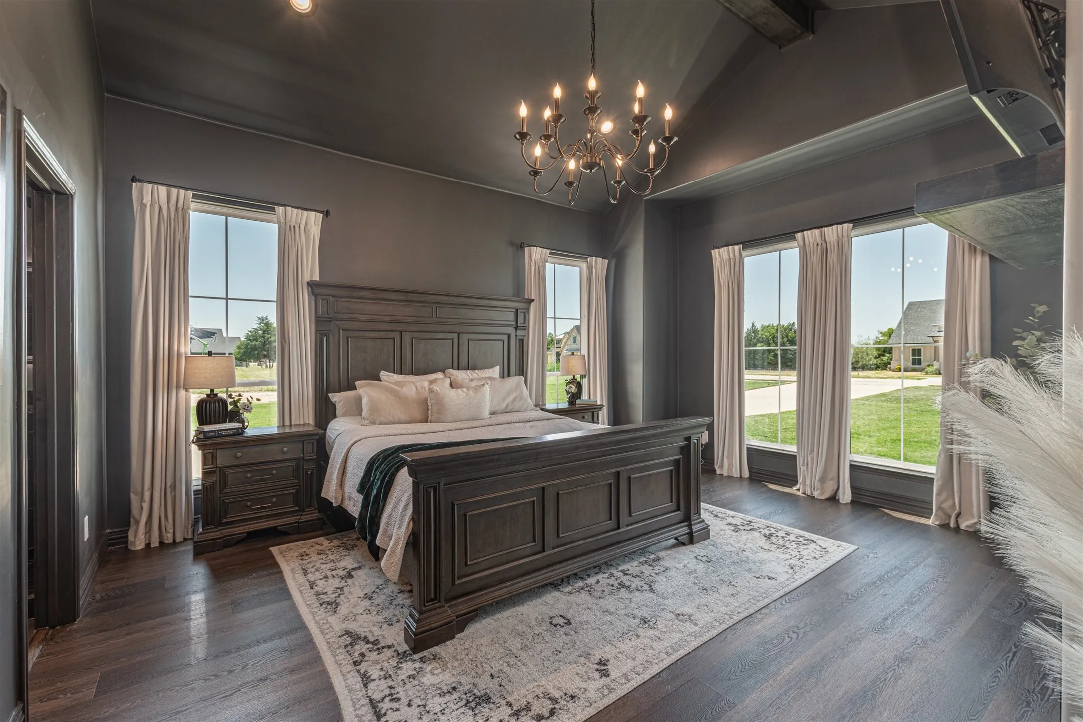 Spacious interior featuring a vaulted ceiling with exposed beam, dark wood-finish flooring, and multiple large windows