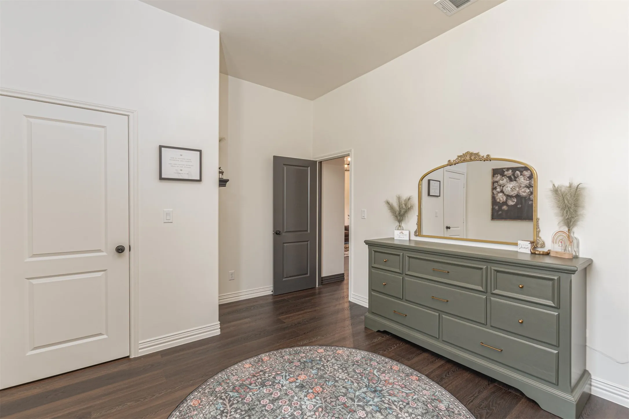Spacious room with dark wood-finish flooring, white walls, and a vaulted ceiling