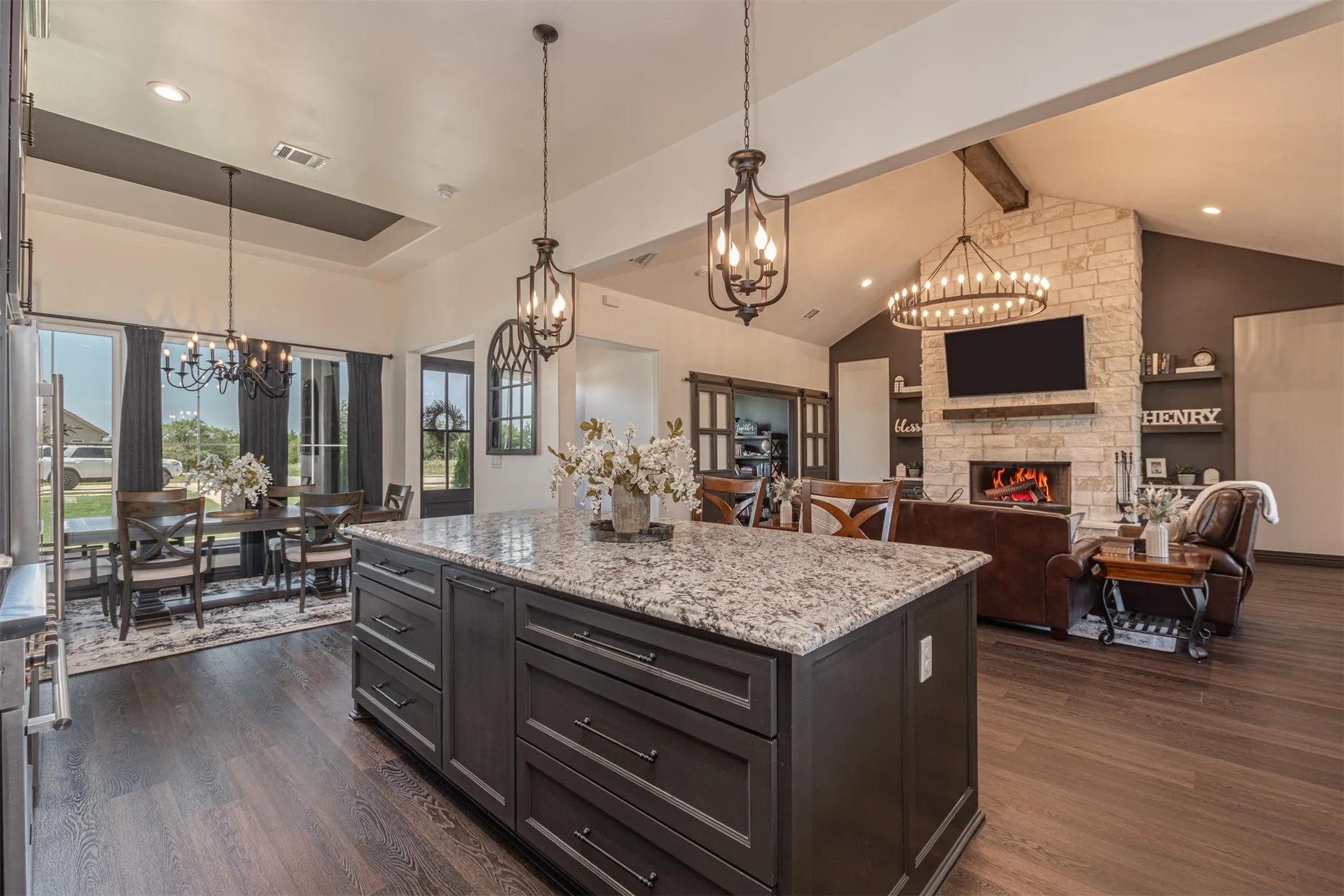 Spacious open-concept interior featuring a substantial kitchen island with a stone-finish countertop, dark wood-finish cabinetry, and pendant lighting