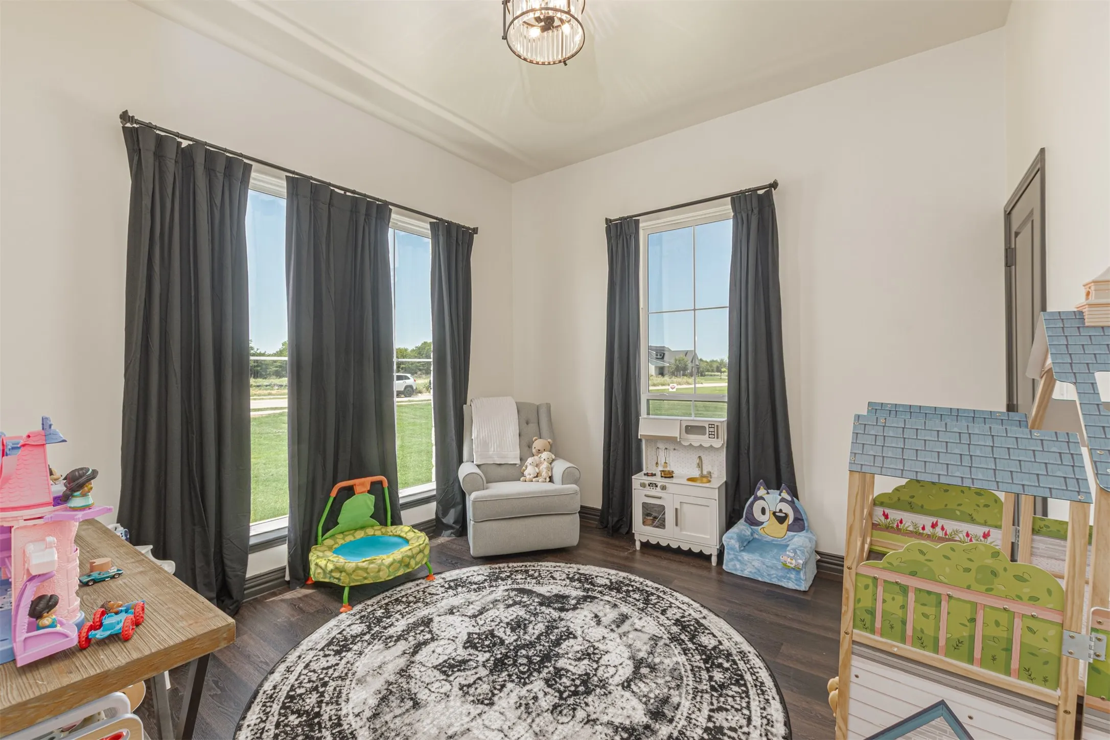 Bright room featuring dark wood-finish flooring and multiple windows with dark drapery