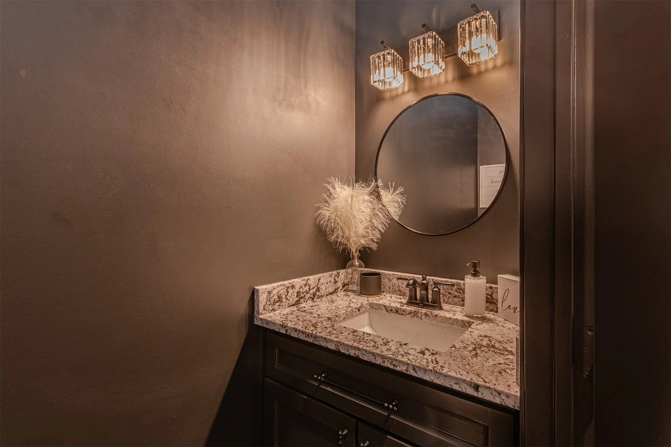 Vanity featuring a dark wood-finish cabinet, speckled stone countertop, and an undermount sink