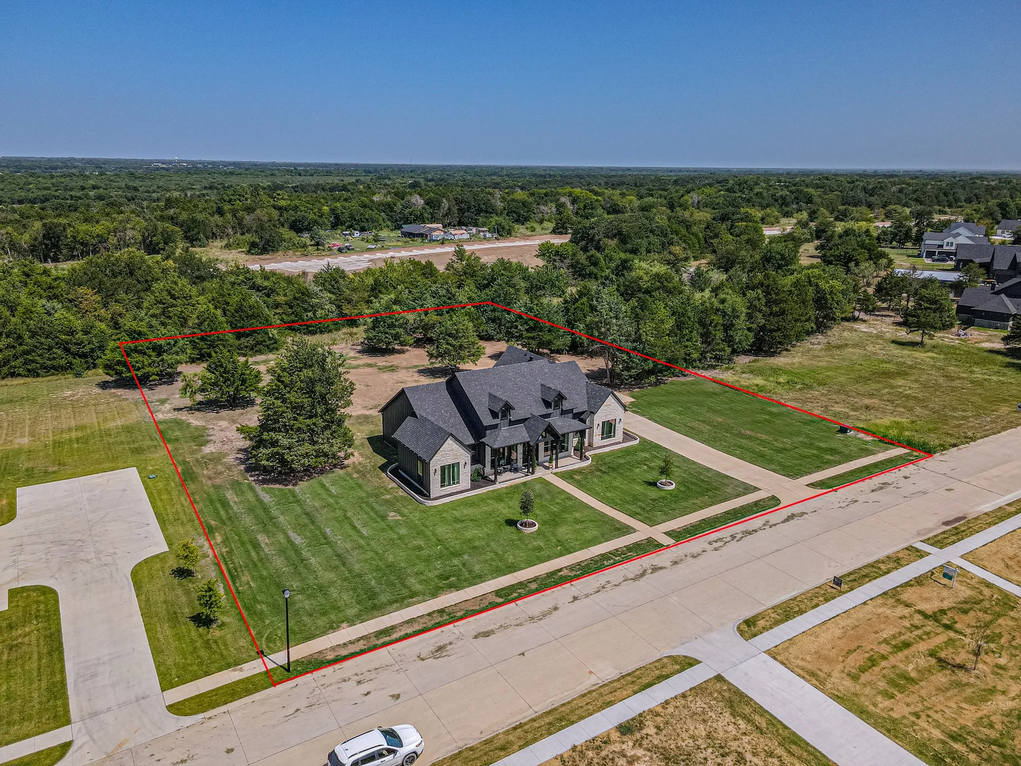 Modern exterior with stone accents and a dark shingle roof, set on a manicured lawn