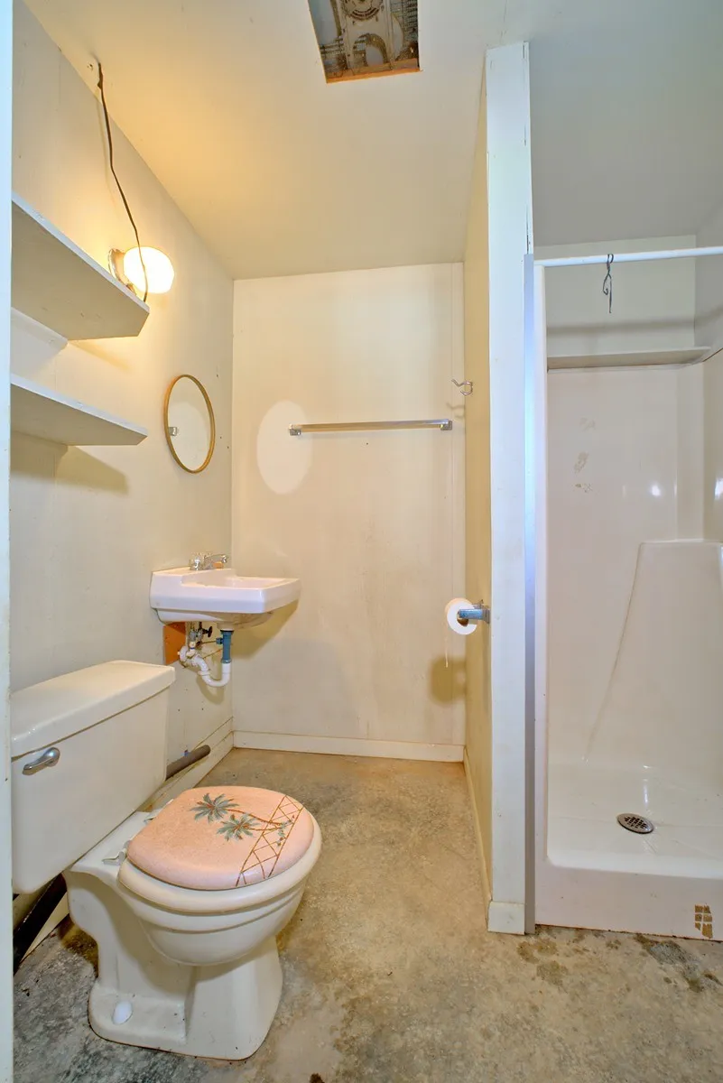 Full Bathroom in garage/workshop - featuring a wall-mounted sink, toilet, and stand-up shower
