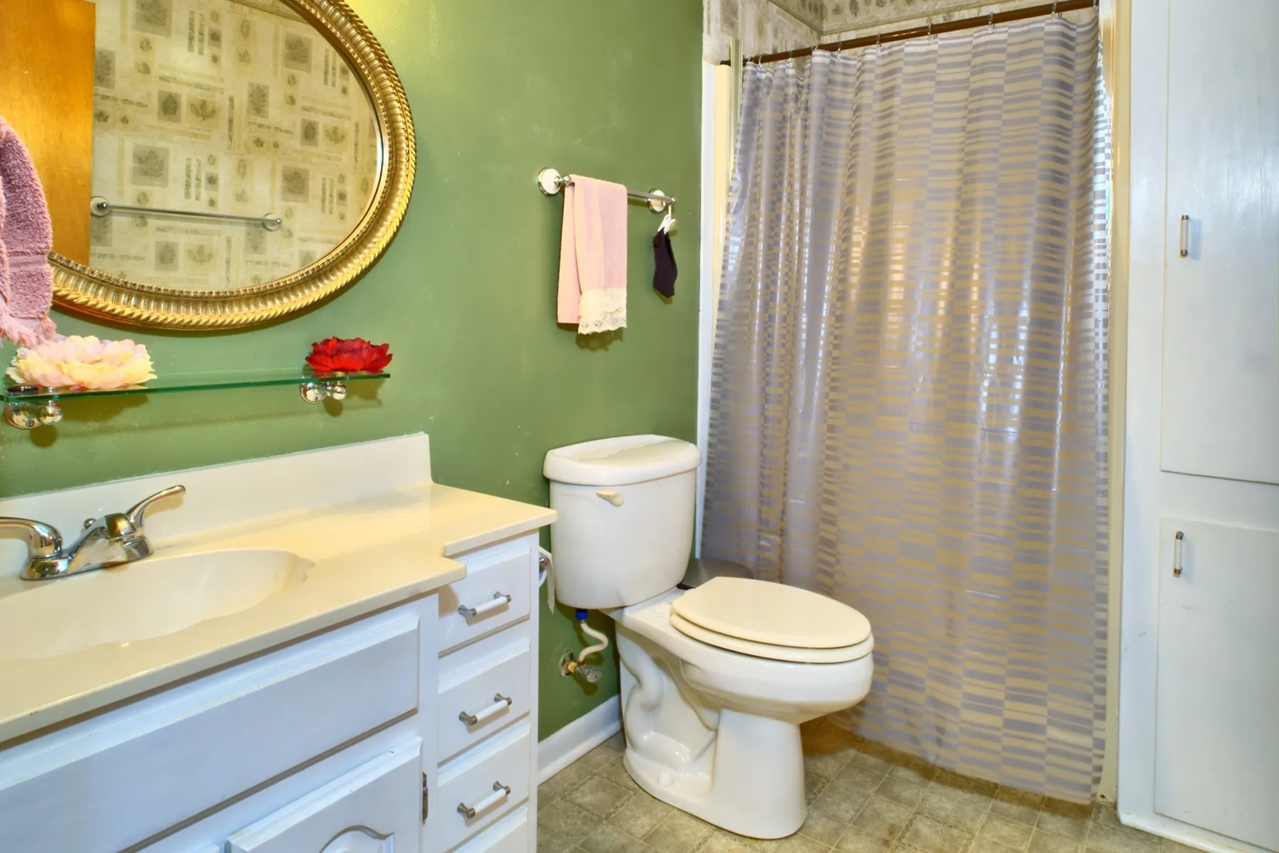 Primary Bathroom - walk in shower - featuring a white vanity with an integrated sink, a gold-framed oval mirror, and a toilet