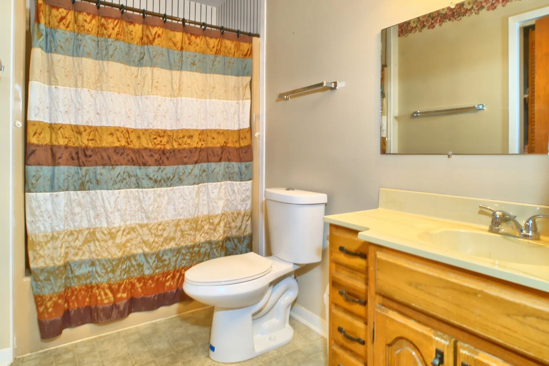 Second full Bathroom featuring a light-toned vanity with an integrated sink and chrome faucet, a wall-mounted mirror, and a white toilet