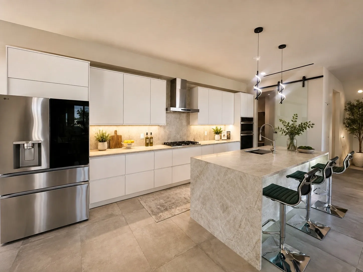 Designer kitchen featuring Taj Mahal quartz stone throughout, waterfall island, custom cabinetry, gas cooktop, stainless steel appliances, double ovens, and contemporary statement lighting.