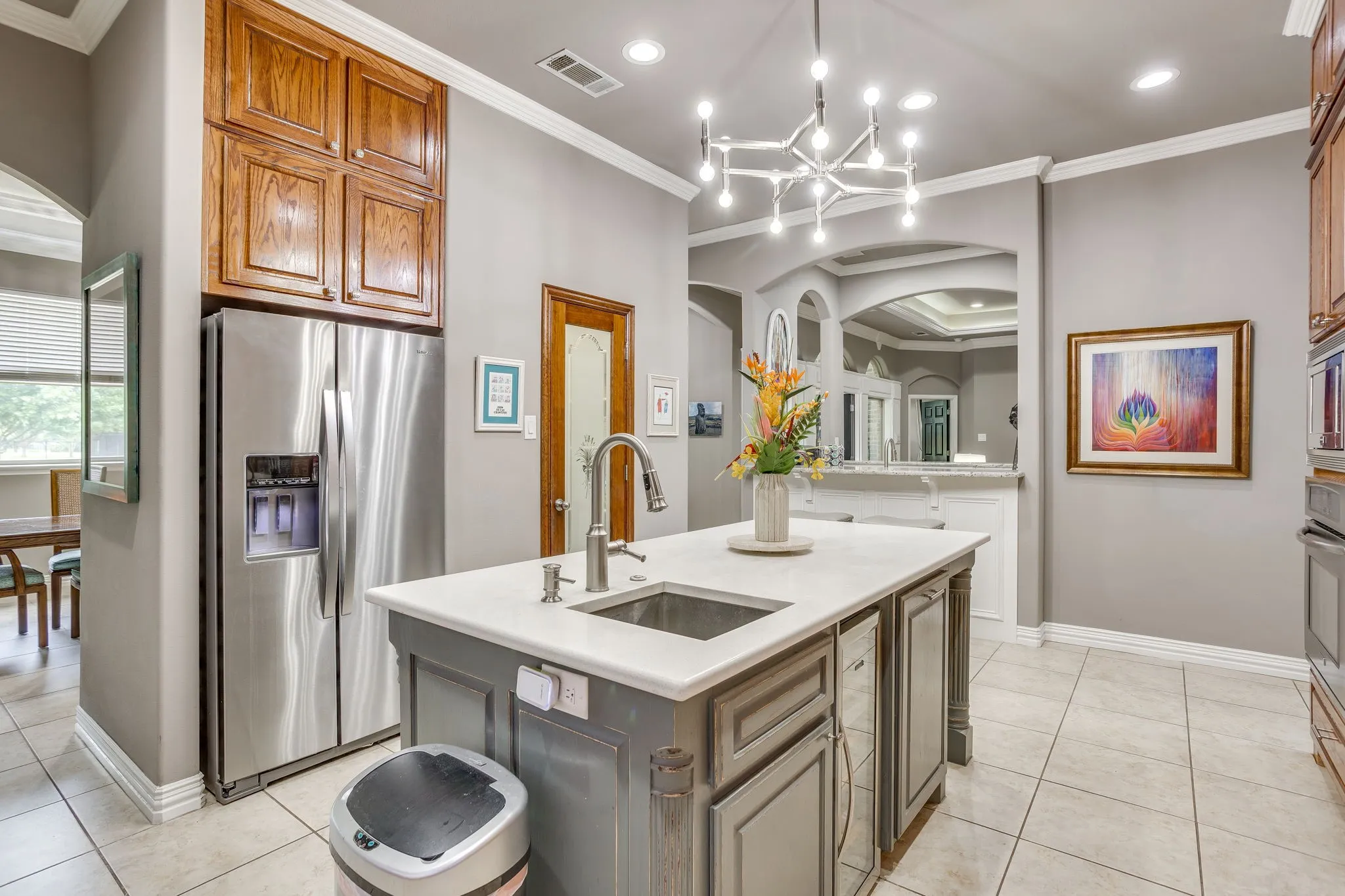 Kitchen island featuring an undermount sink, gooseneck faucet, and light-toned countertop