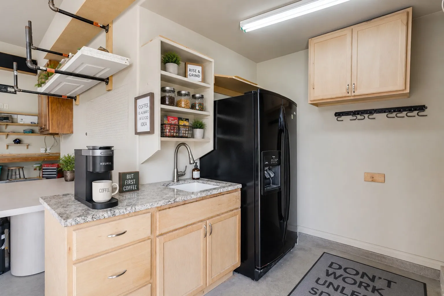 Garage Utility space featuring a built-in countertop with an undermount sink, granite-finish surface, and light wood cabinetry