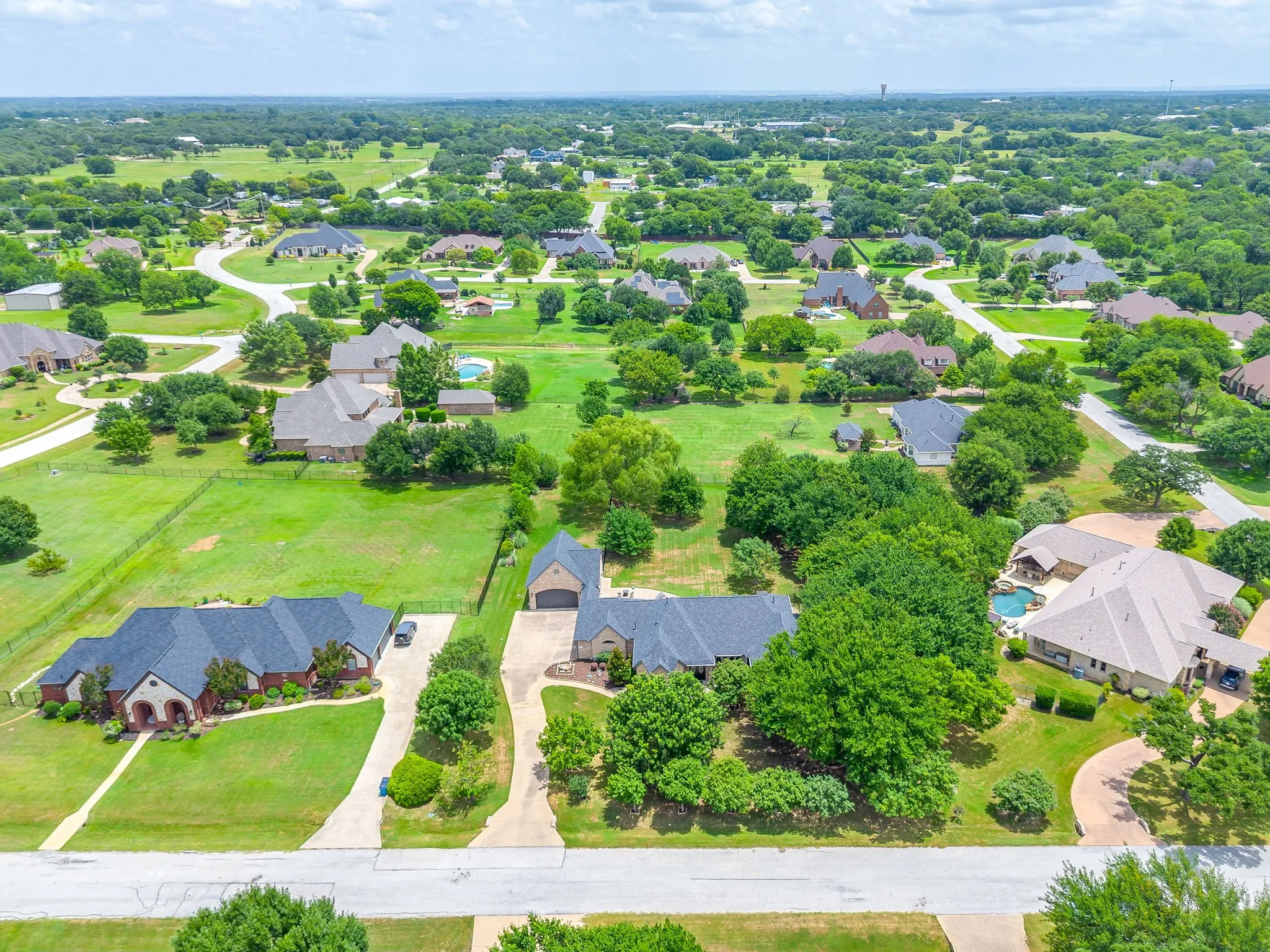Expansive aerial view showcasing multiple properties amidst extensive green landscaping