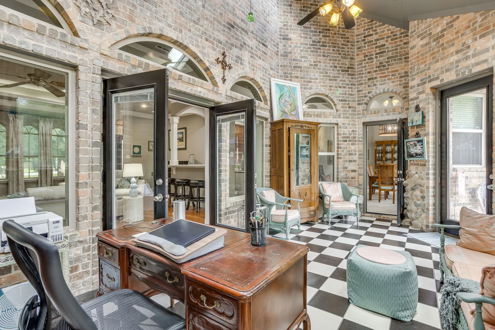 Sunroom with exposed brick walls, a high vaulted ceiling, and black and white checkered flooring