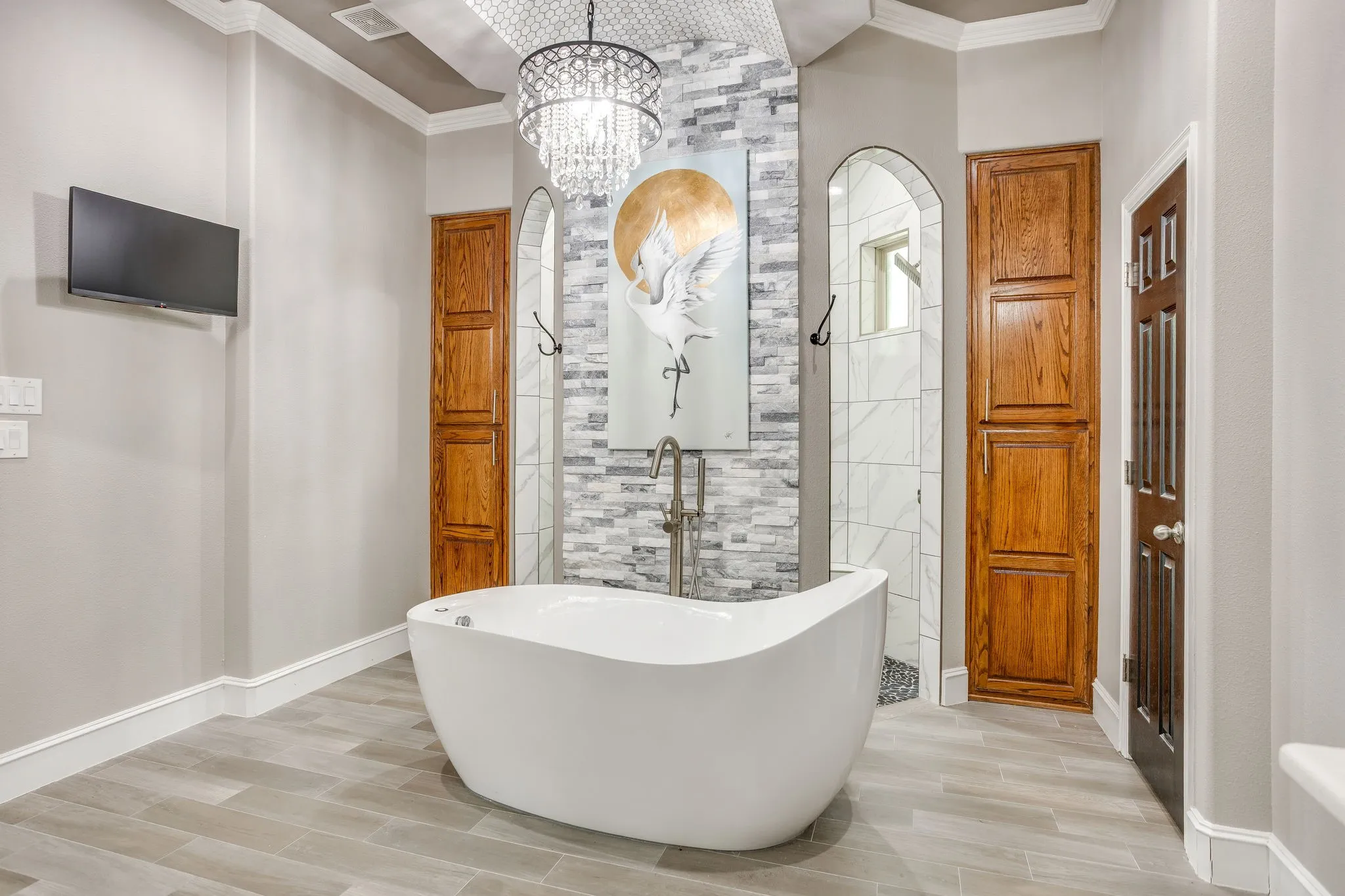 Freestanding soaking tub with a floor-mounted faucet, set against a tiled accent wall