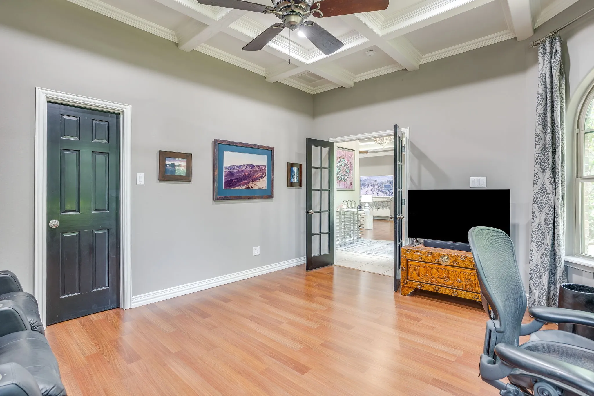 Hardwood-finish flooring highlights this room featuring a coffered ceiling with a ceiling fan